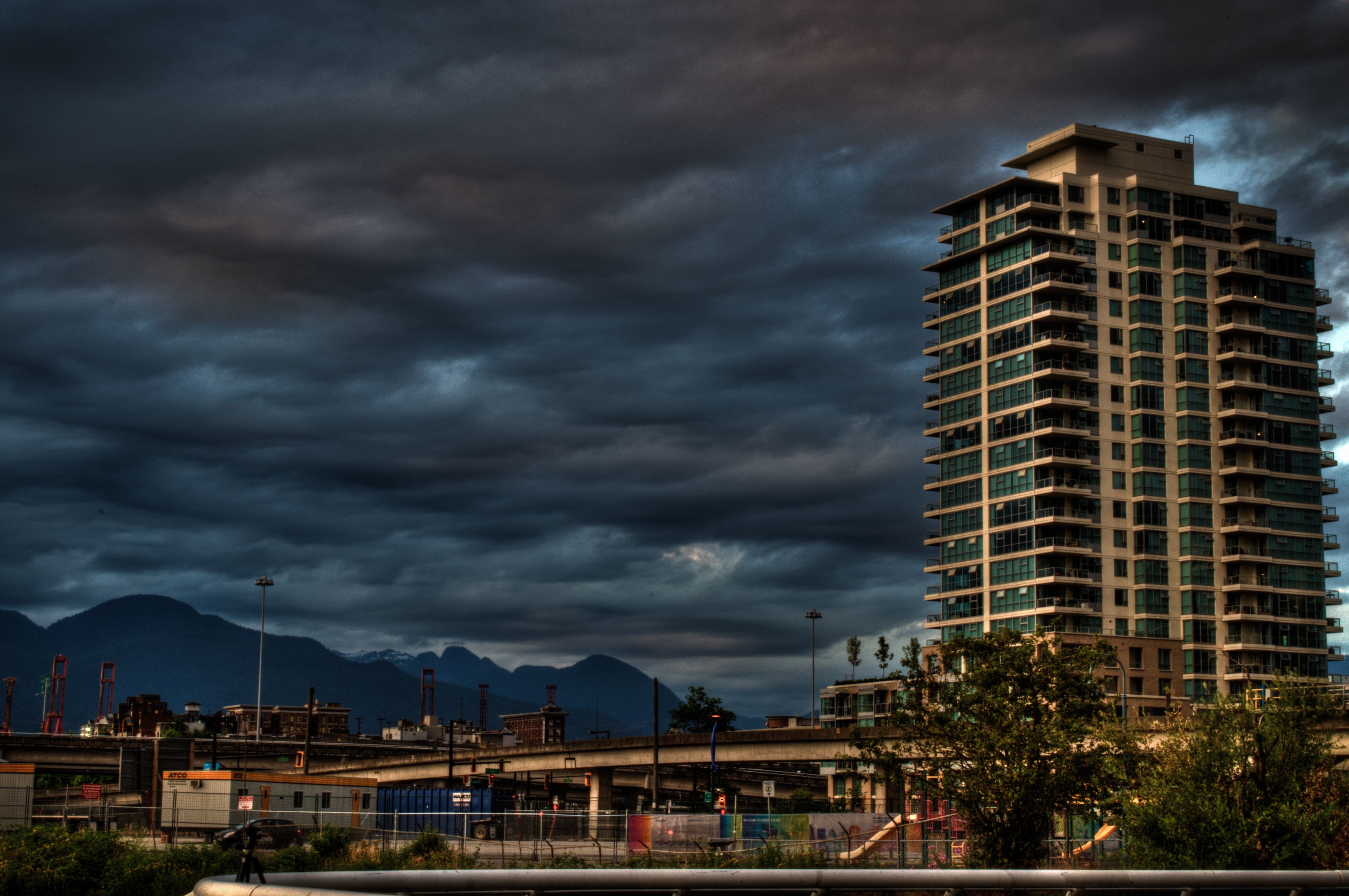 Apartment building against stormy sky and mountains HD Wallpaper