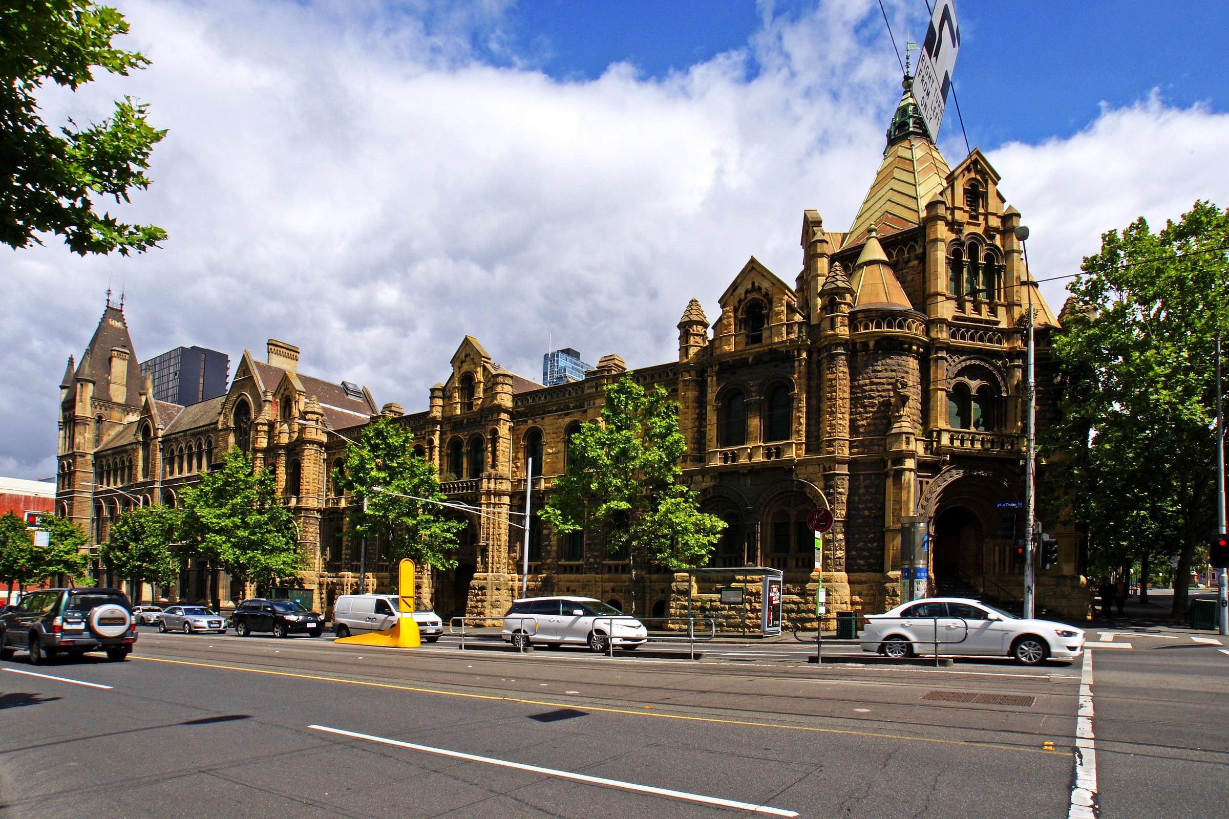 Old stone building with trees and cars in Australia HD Wallpaper