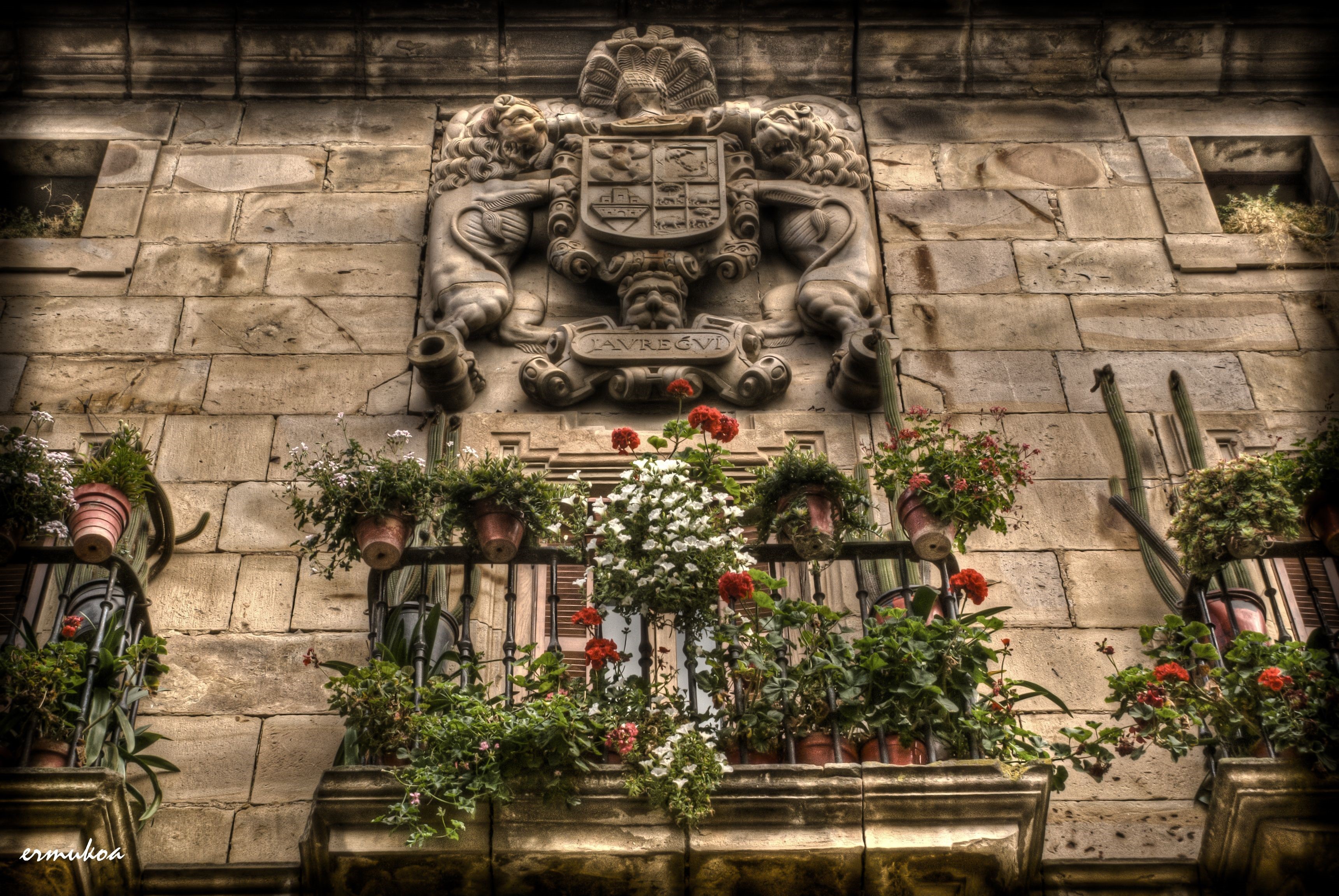 Coat of arms above balconies with flowers in Spain HD Wallpaper