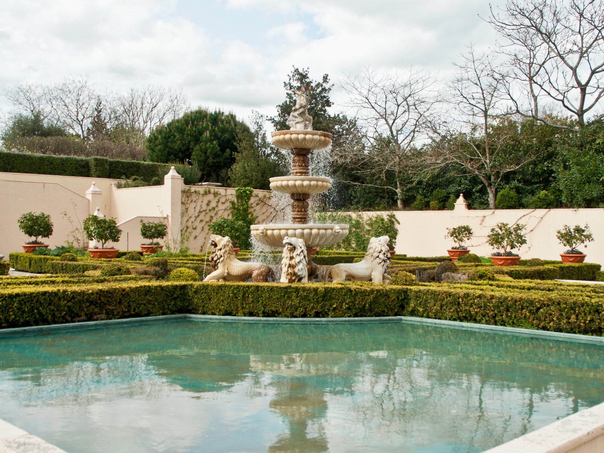 Fountain with lion statues in a formal garden HD Wallpaper