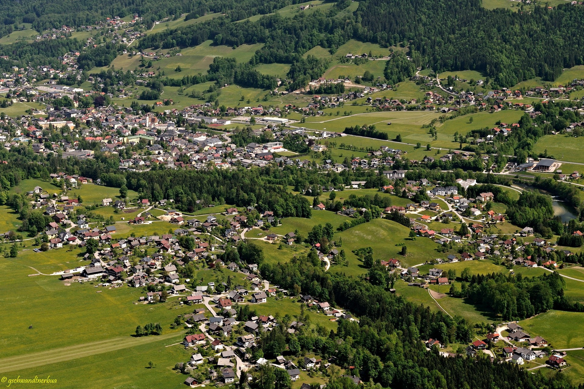 Aerial view of a town in Austria with rolling green hills HD Wallpaper