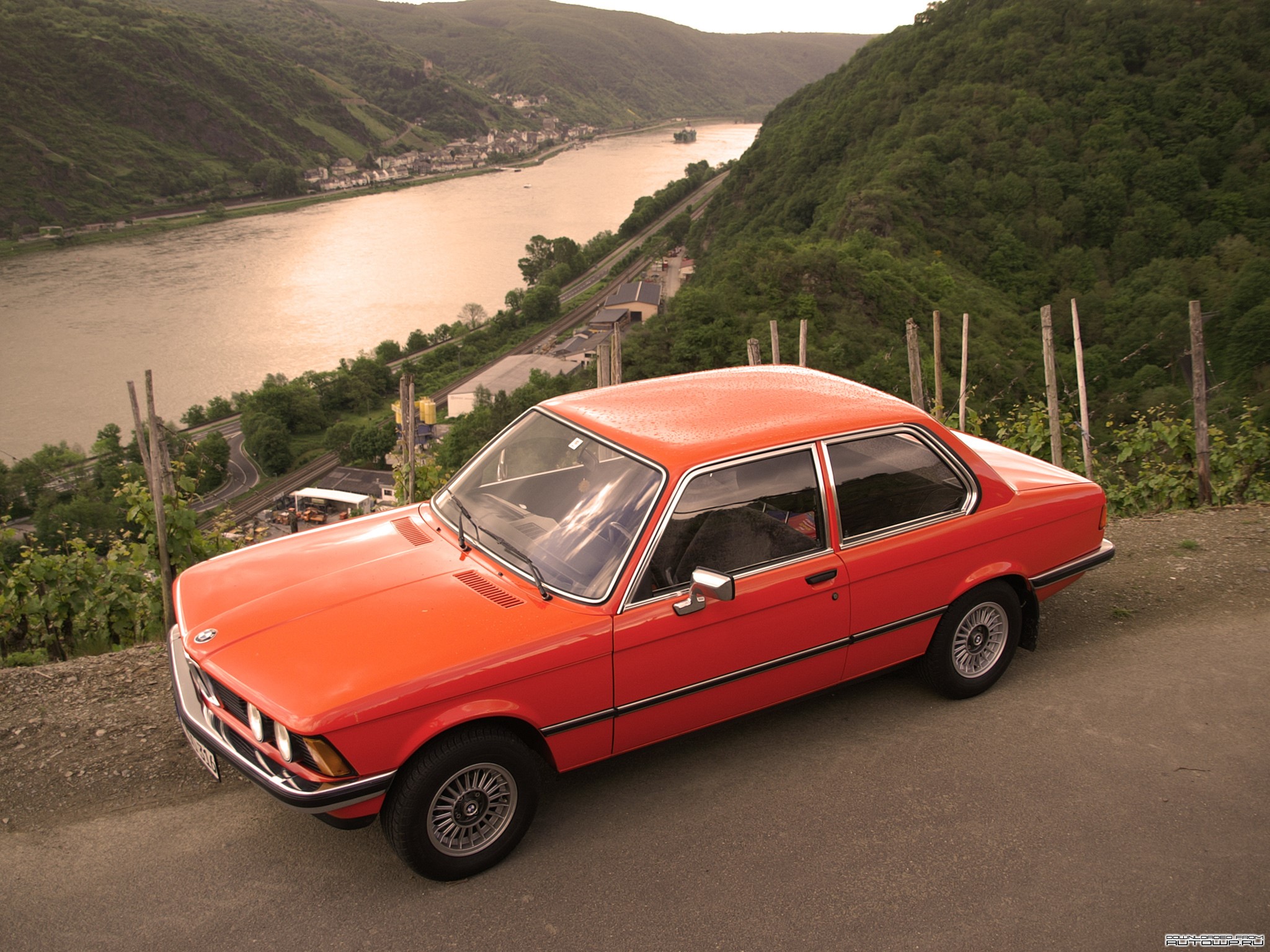 Red BMW parked on a hill overlooking a river valley HD Wallpaper