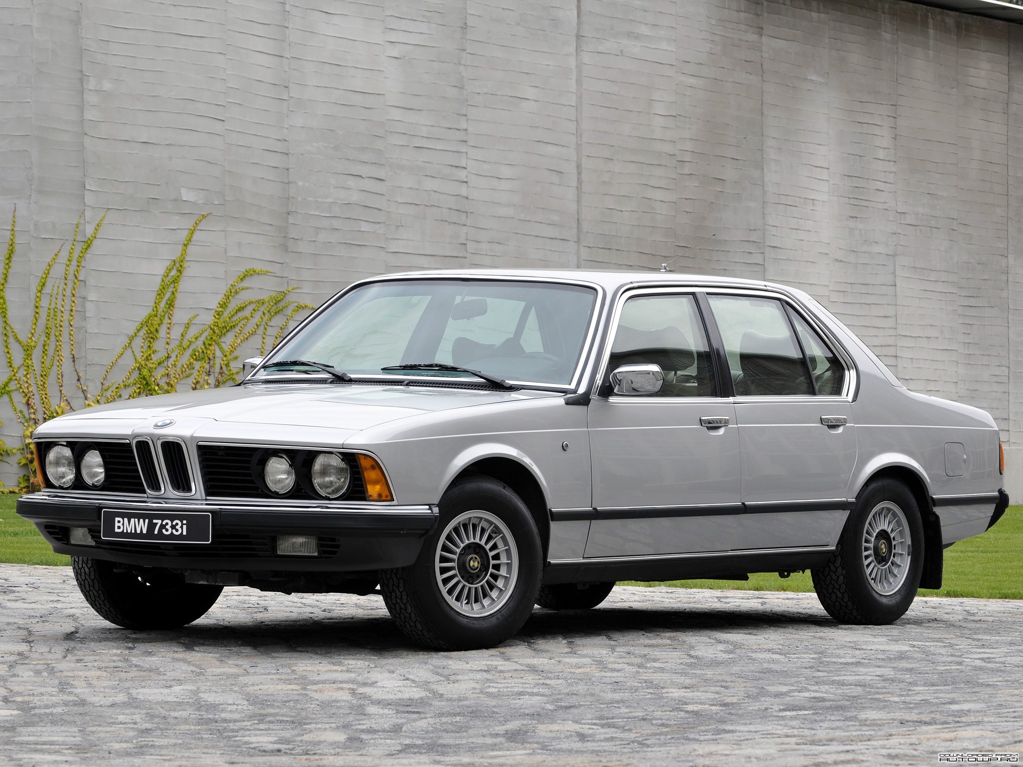 Silver BMW 733i parked in front of a textured wall HD Wallpaper