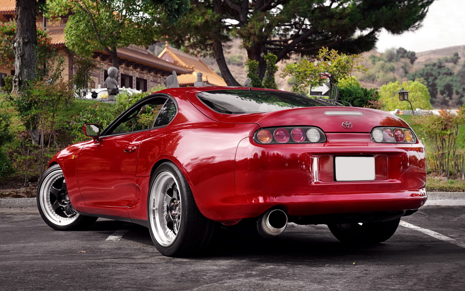 Red Toyota Supra parked near a Buddhist temple HD Wallpaper