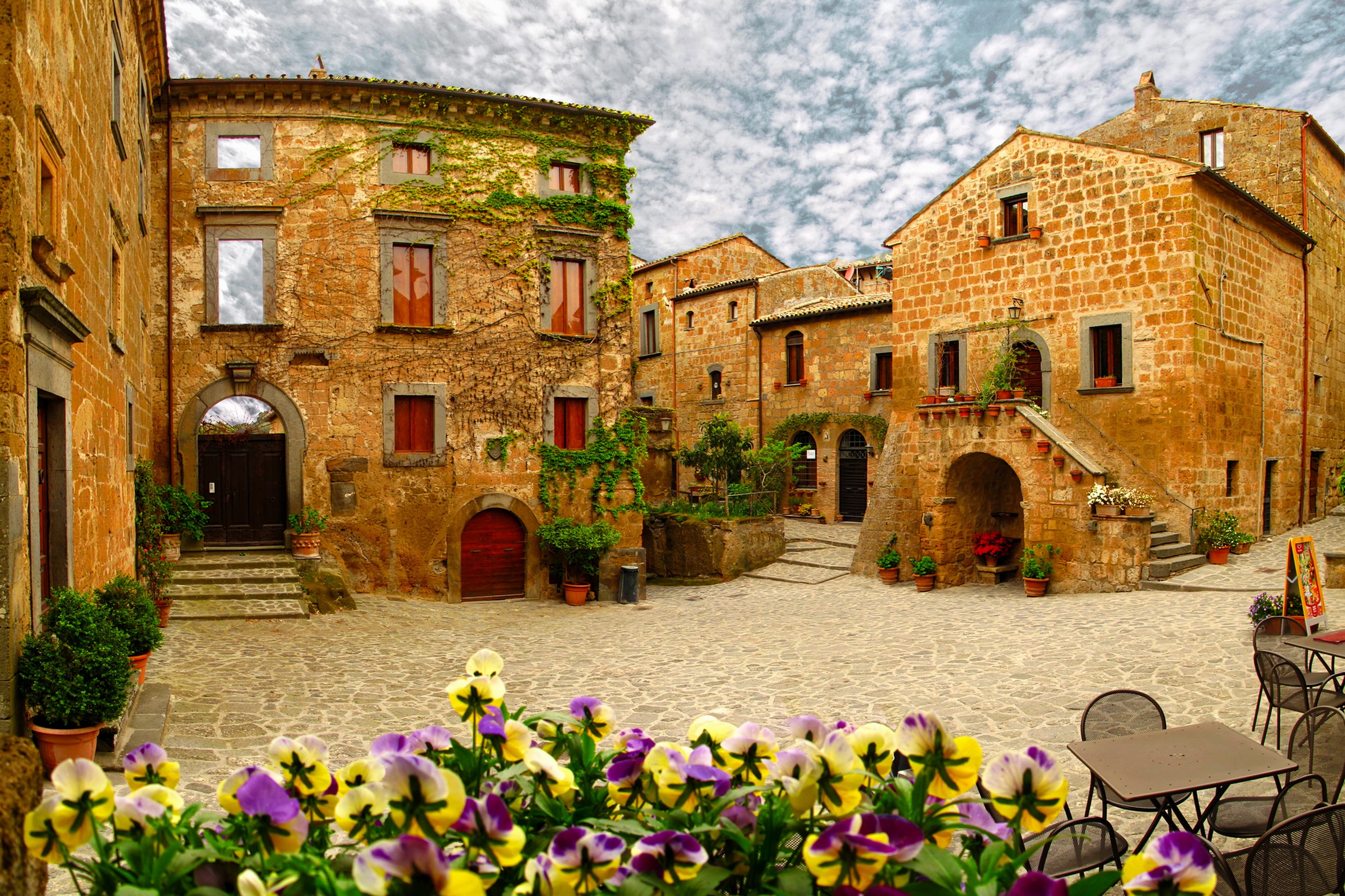 Italian village square with flowers and buildings HD Wallpaper