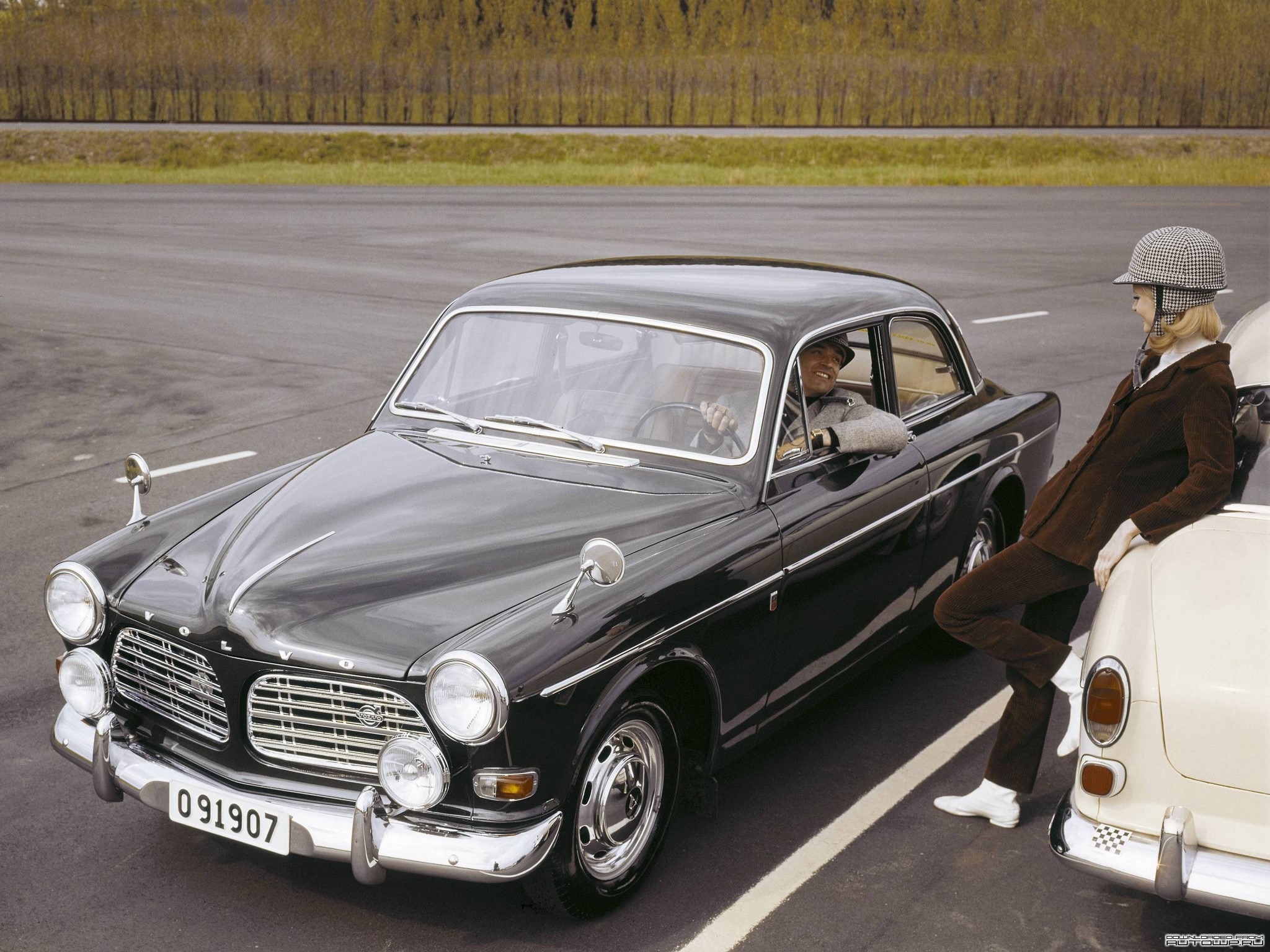 Man driving a Volvo P123 GT with a woman leaning on another car HD Wallpaper