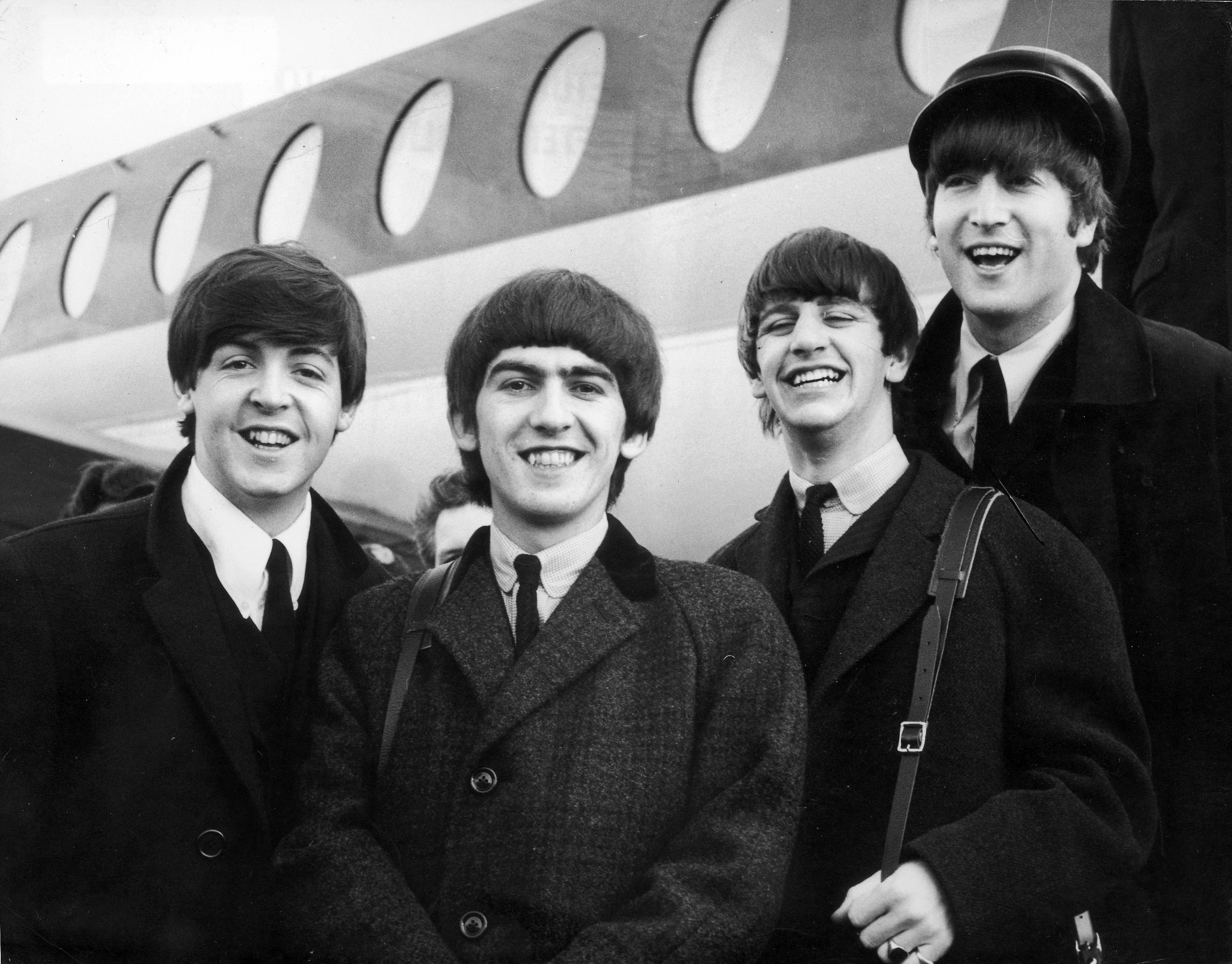 The Beatles posing in front of an airplane HD Wallpaper
