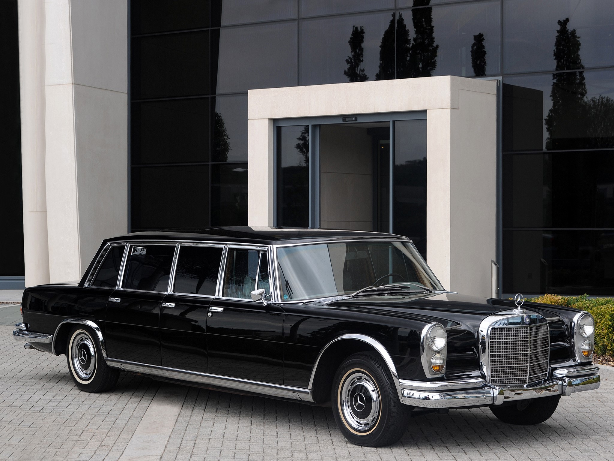 Black Mercedes-Benz Pullman limousine parked outside modern building HD Wallpaper