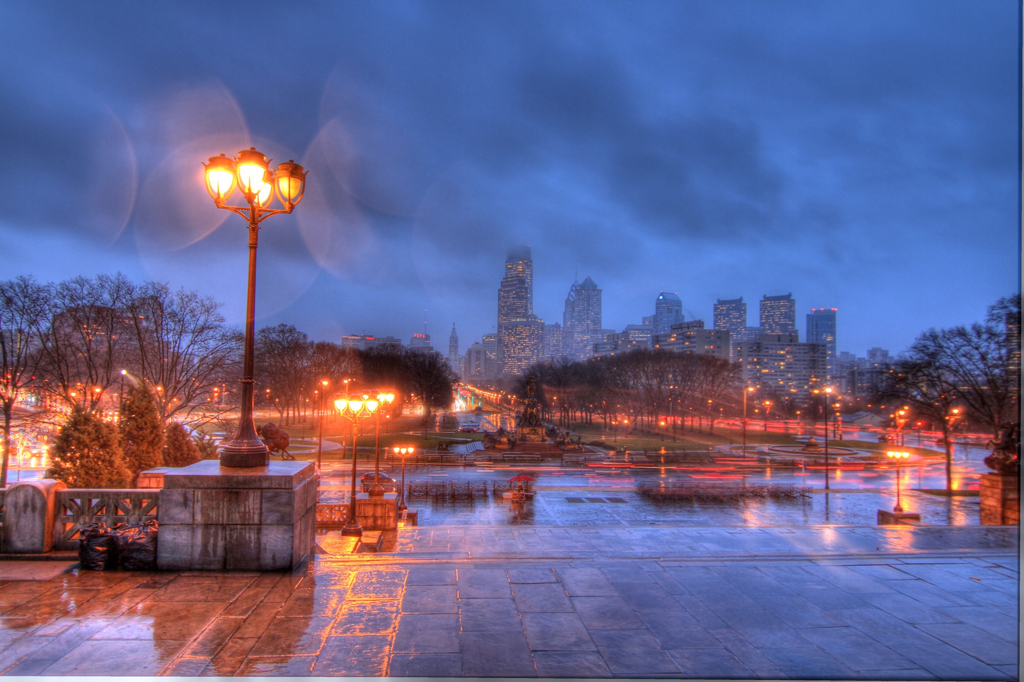 Philadelphia skyline at night with streetlights and wet pavement HD Wallpaper
