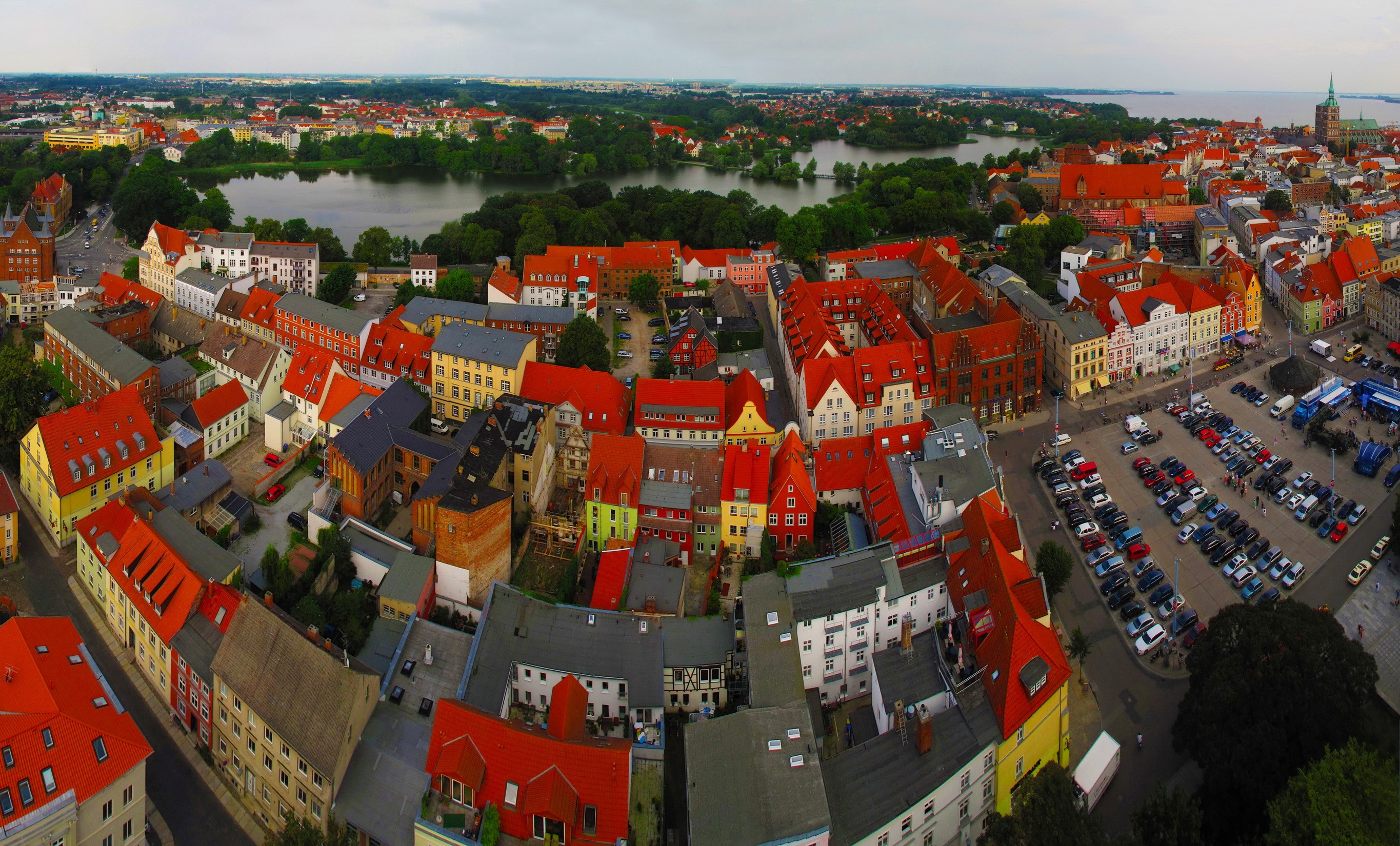 Aerial view of a European city with red roofs and a lake HD Wallpaper