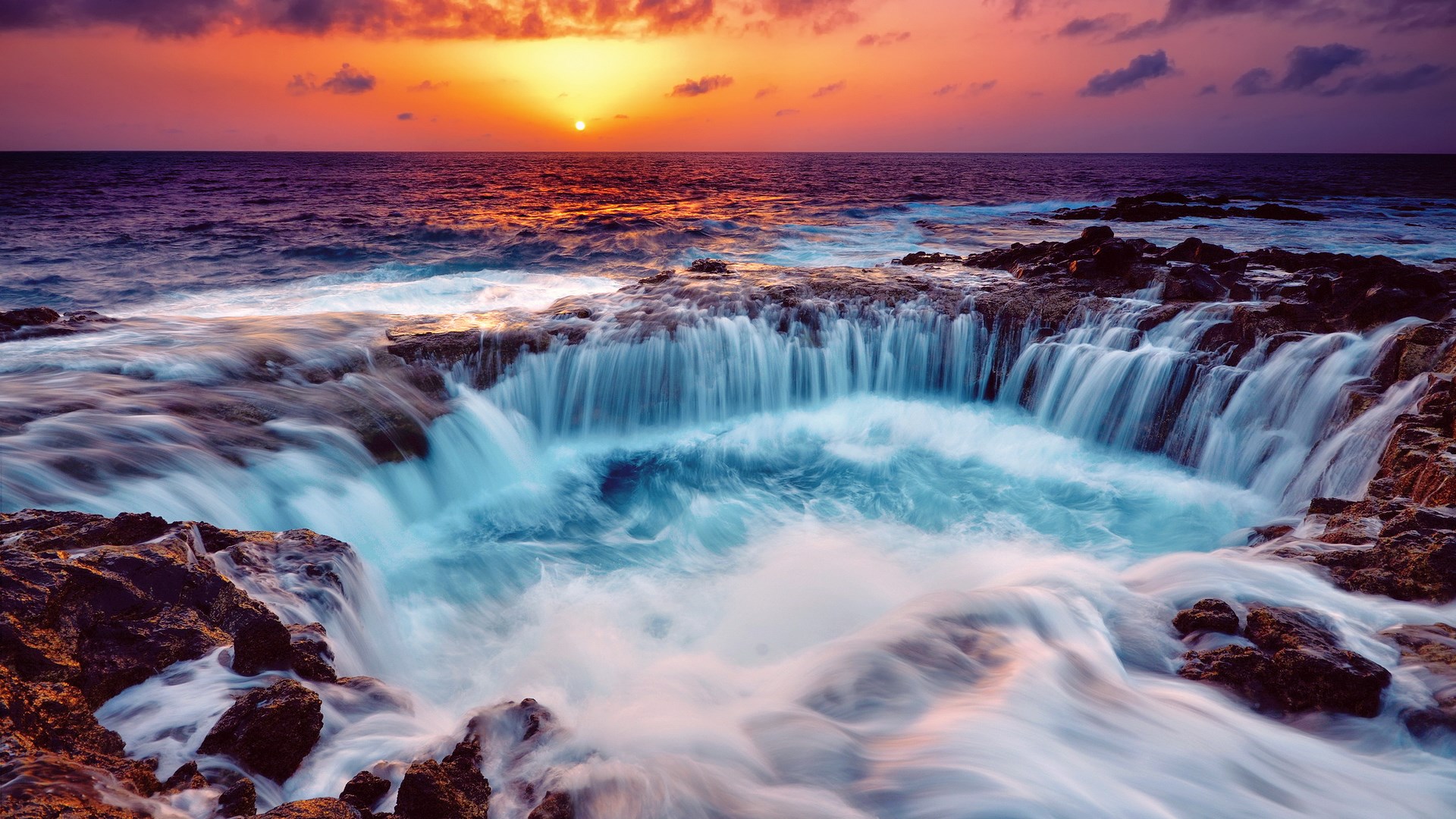 Ocean waves crashing over rocky shore at sunset HD Wallpaper
