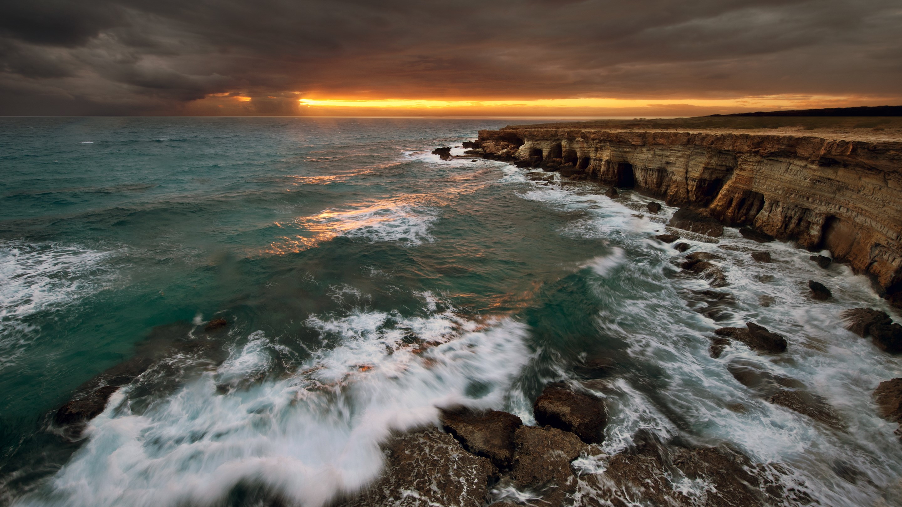 Waves crashing on rocky cliffs at sunset HD Wallpaper