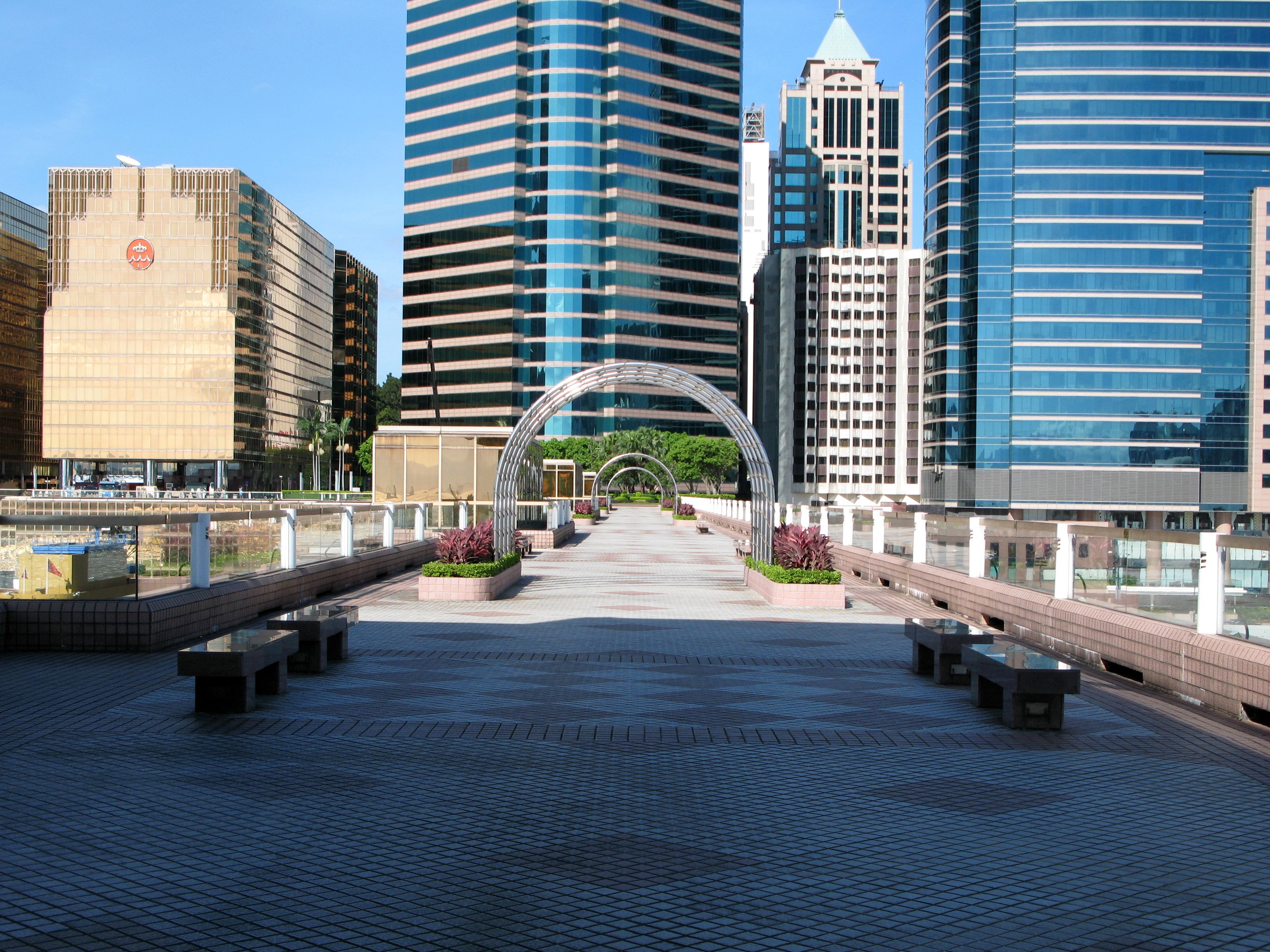 Modern cityscape with skyscrapers and a pedestrian walkway HD Wallpaper