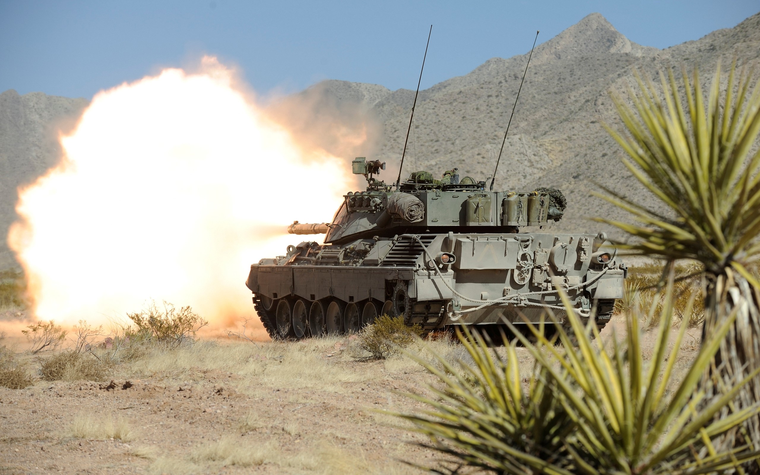 Tank firing a round in a desert landscape HD Wallpaper