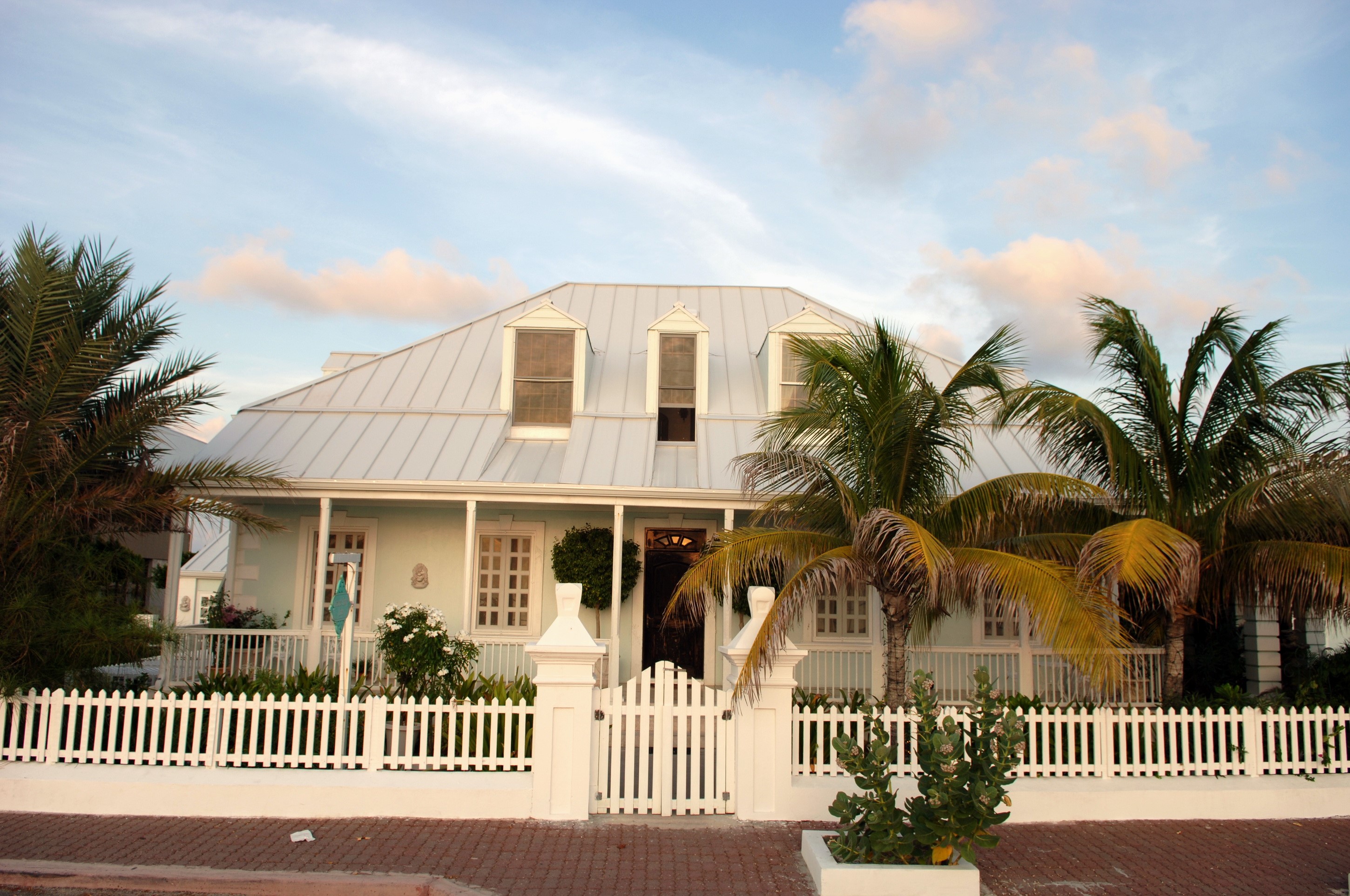 Light blue house with white picket fence and palm trees HD Wallpaper