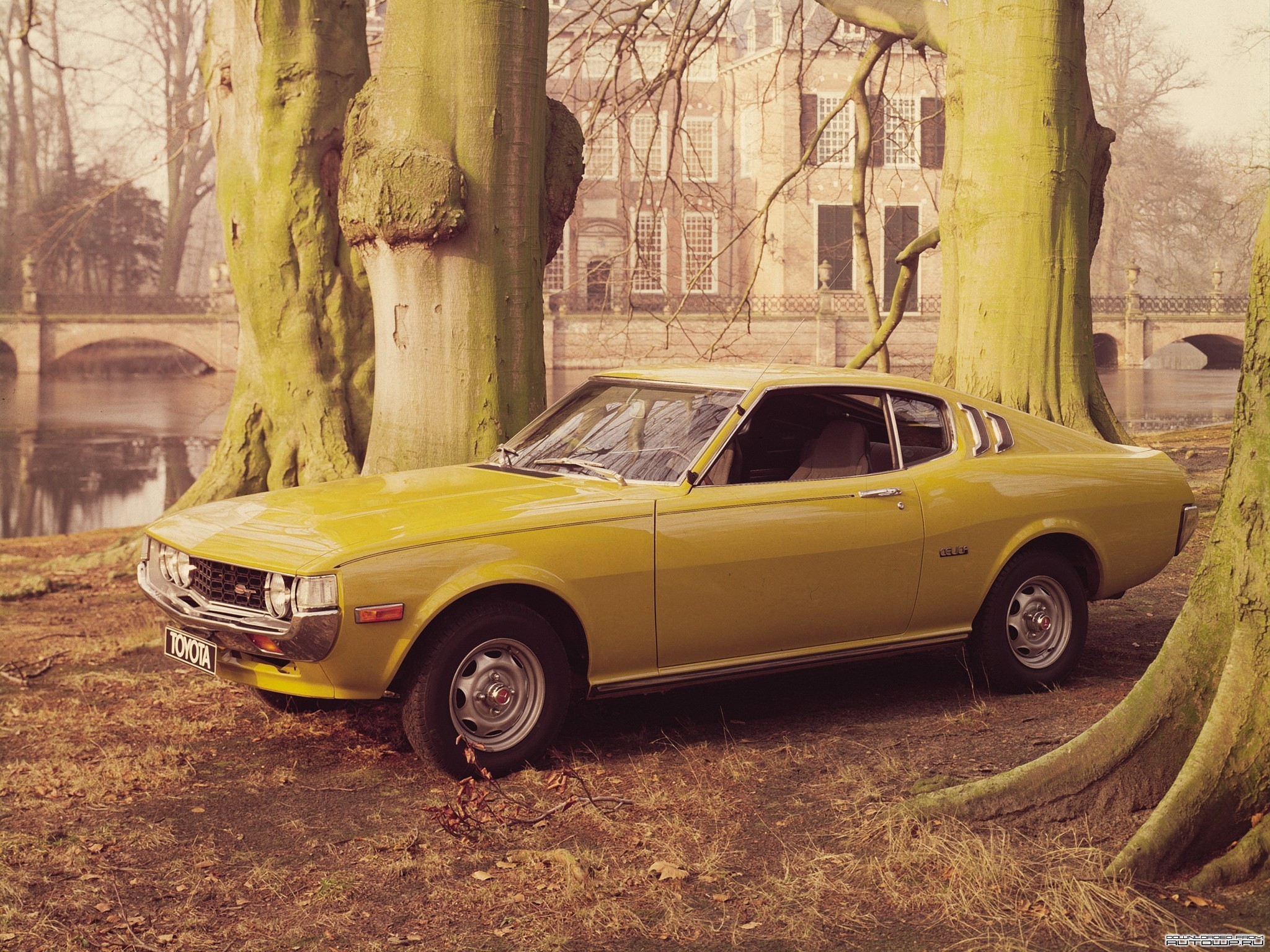 Yellow Toyota Celica parked by trees and a building HD Wallpaper