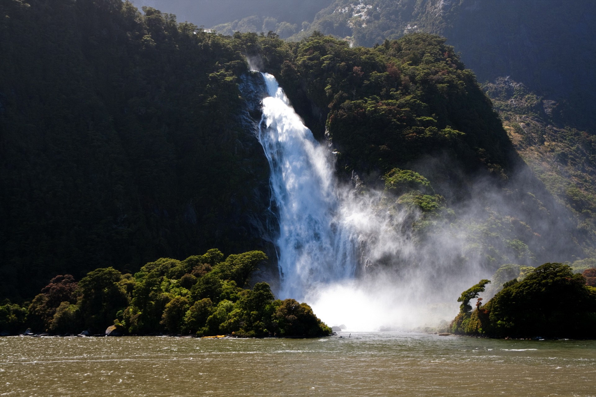 Waterfall cascading into a body of water surrounded by lush green forest HD Wallpaper