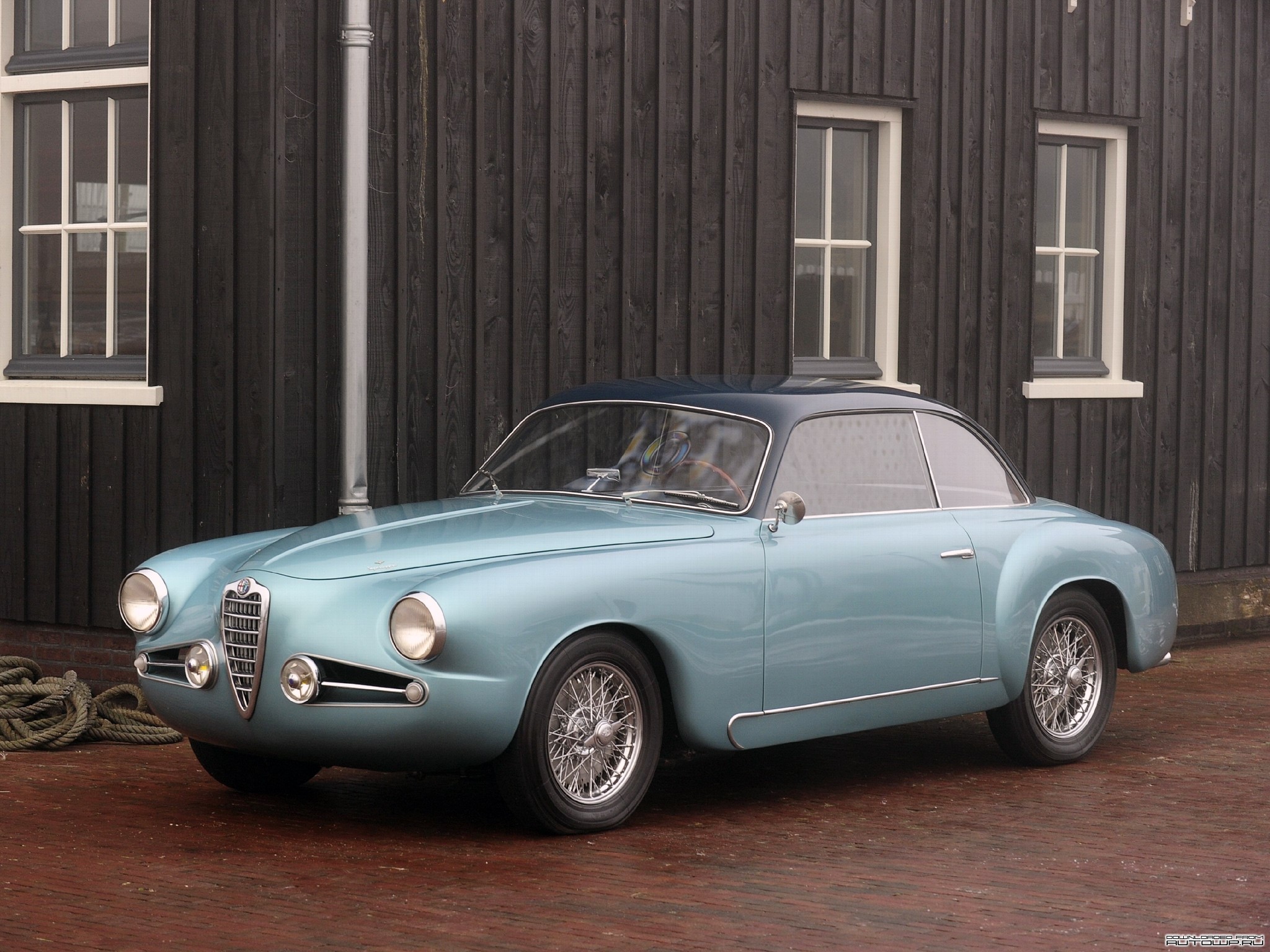 Light blue Alfa Romeo coupe parked outside wooden building HD Wallpaper