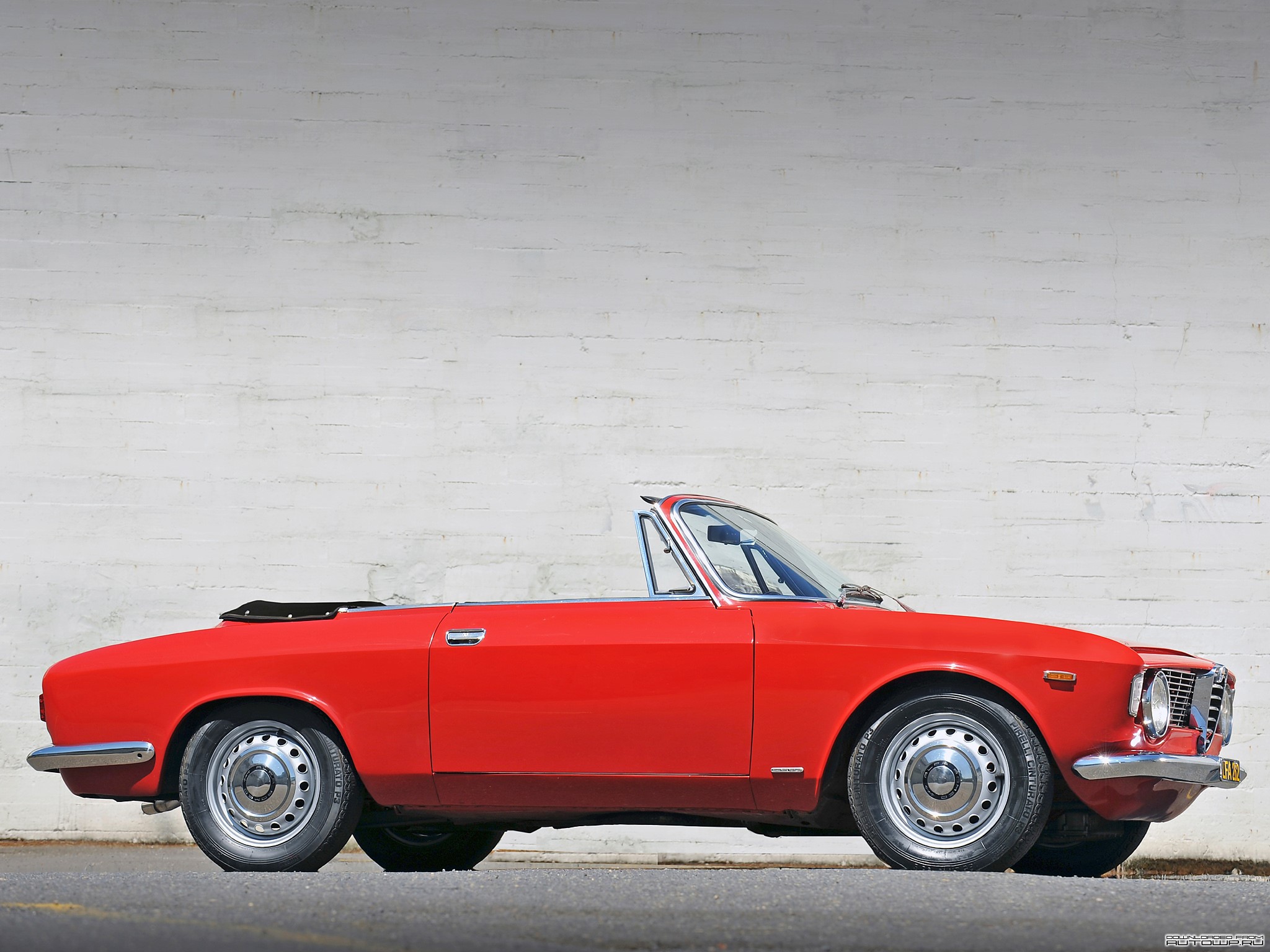 Red Alfa Romeo Convertible parked against a white brick wall HD Wallpaper