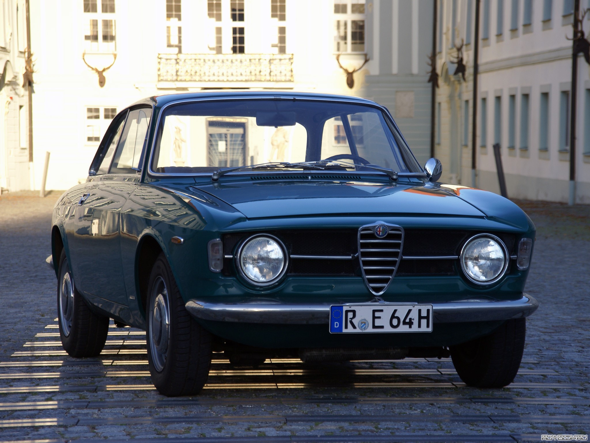 Green Alfa Romeo car parked on cobblestone street HD Wallpaper