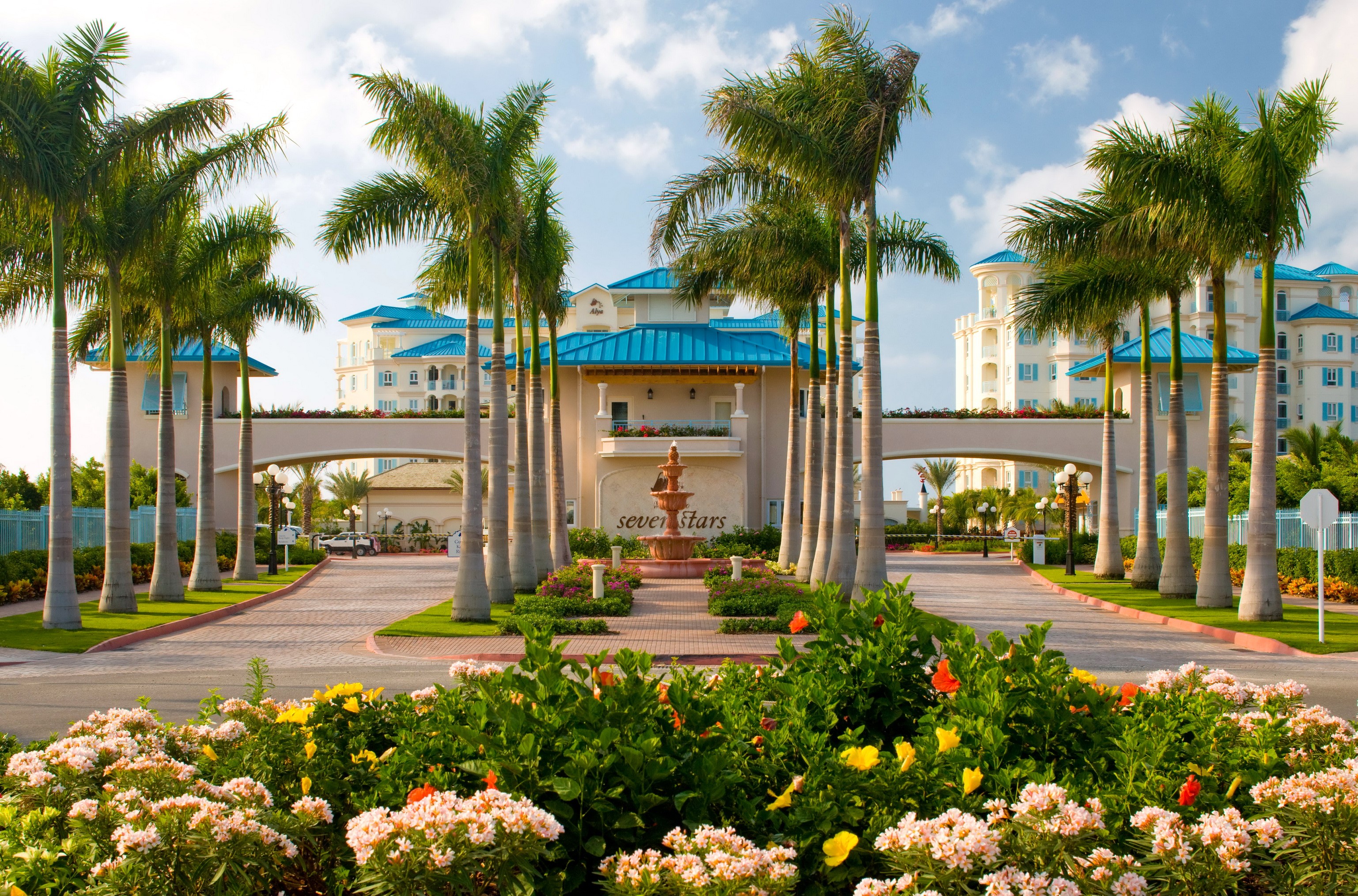 Seven Stars Resort entrance with palm trees and flowers HD Wallpaper