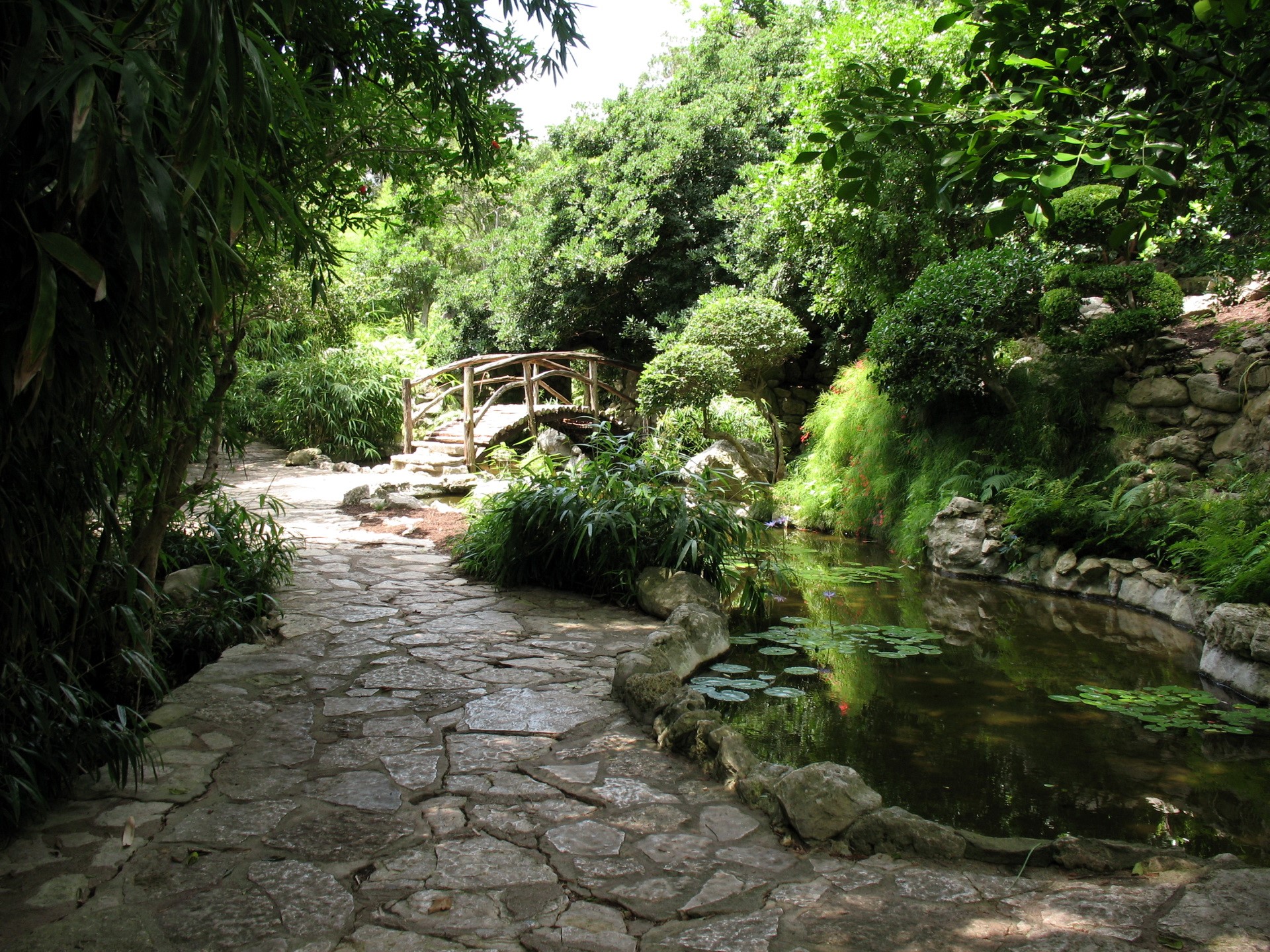 Stone path and wooden bridge in a garden HD Wallpaper