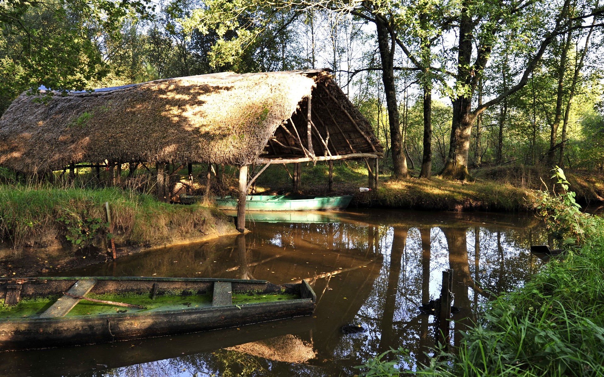 Thatched boathouse on a calm lake with boats HD Wallpaper