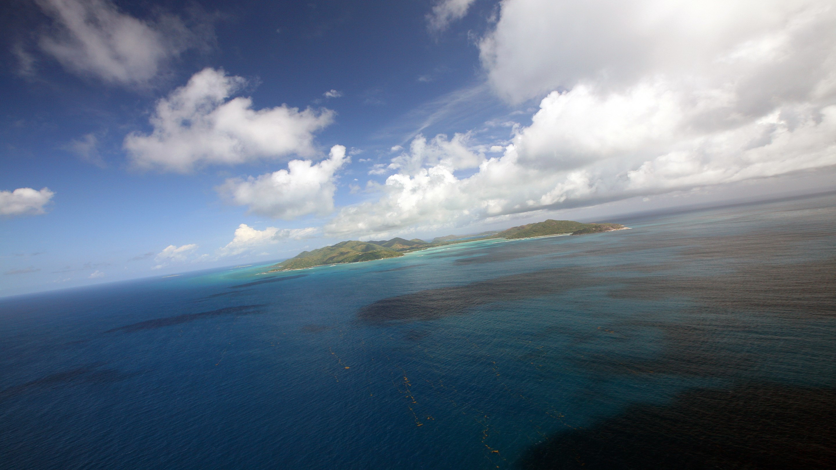 Aerial view of islands and ocean under a cloudy sky HD Wallpaper