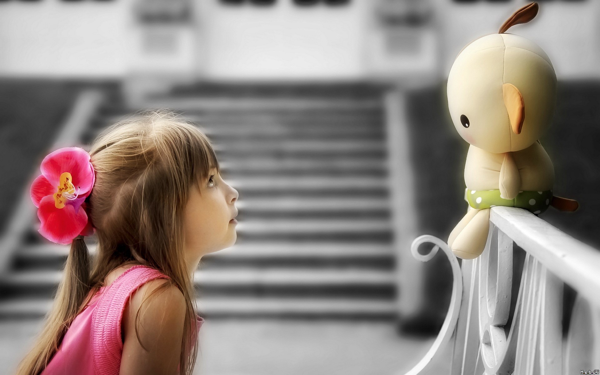 Girl with flower in hair looking at stuffed toy HD Wallpaper
