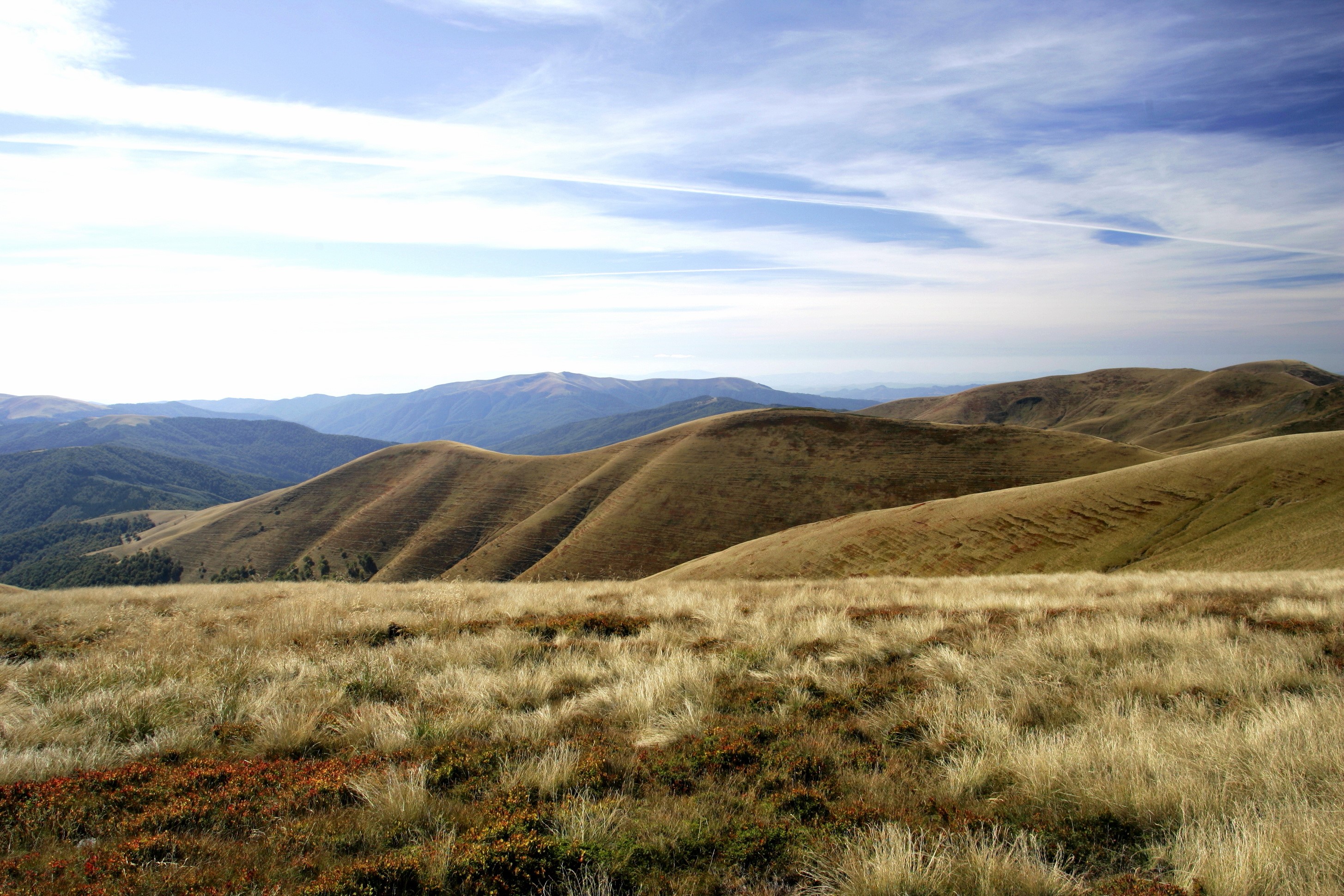 Rolling hills and mountains under a cloudy sky HD Wallpaper