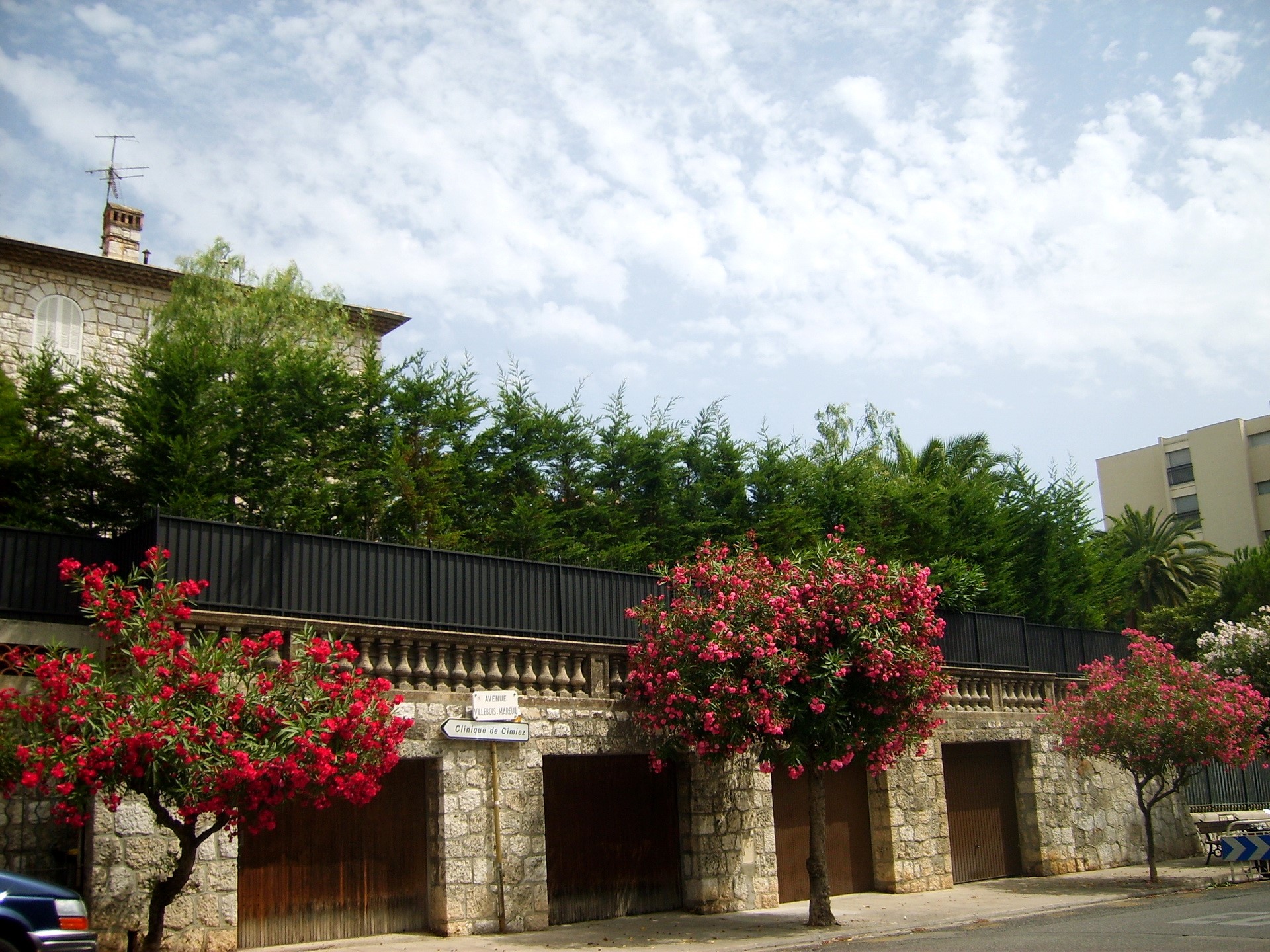 Stone building with garages and flowering trees in France HD Wallpaper