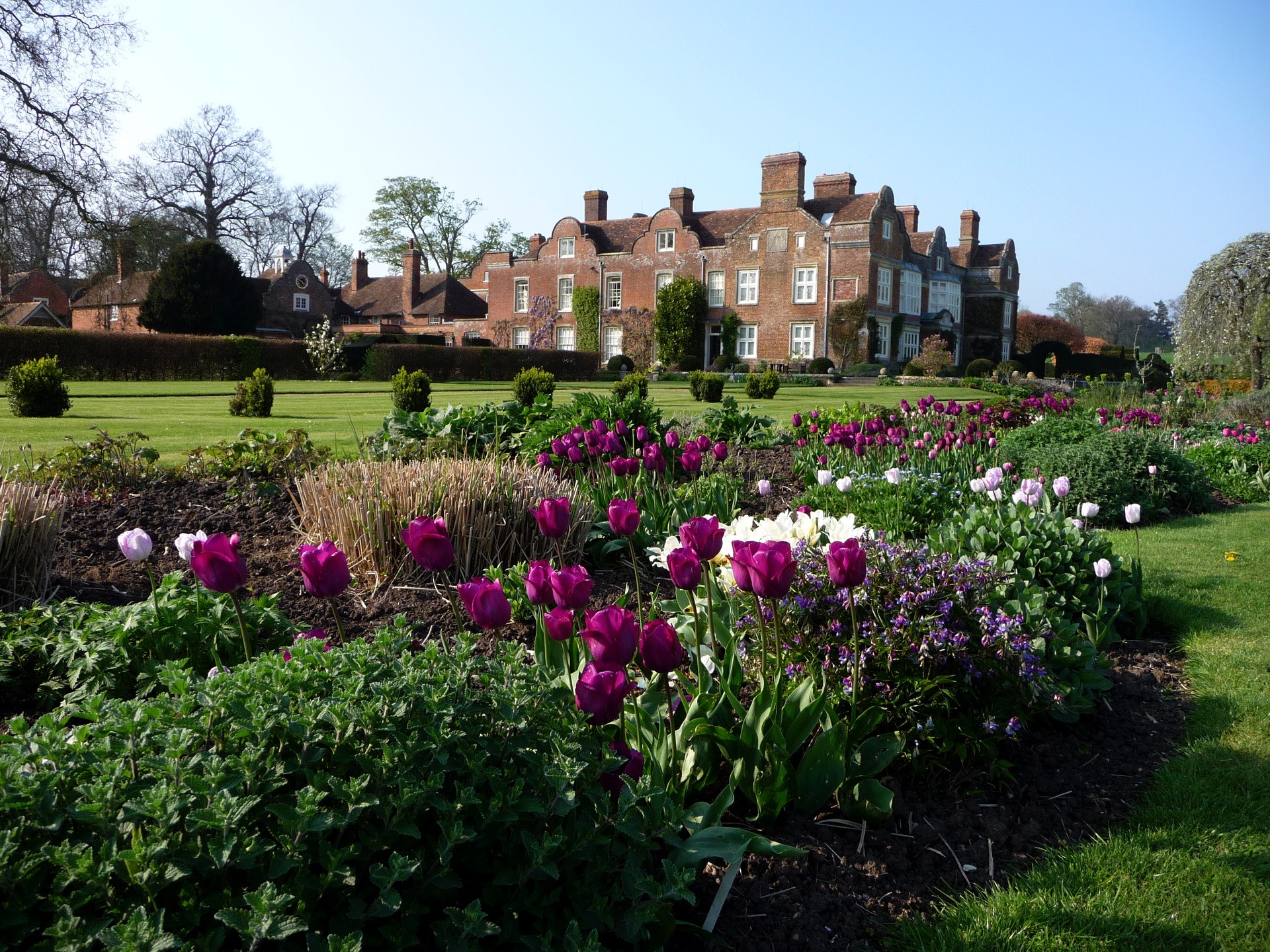 A large brick manor house with a formal garden in the UK HD Wallpaper