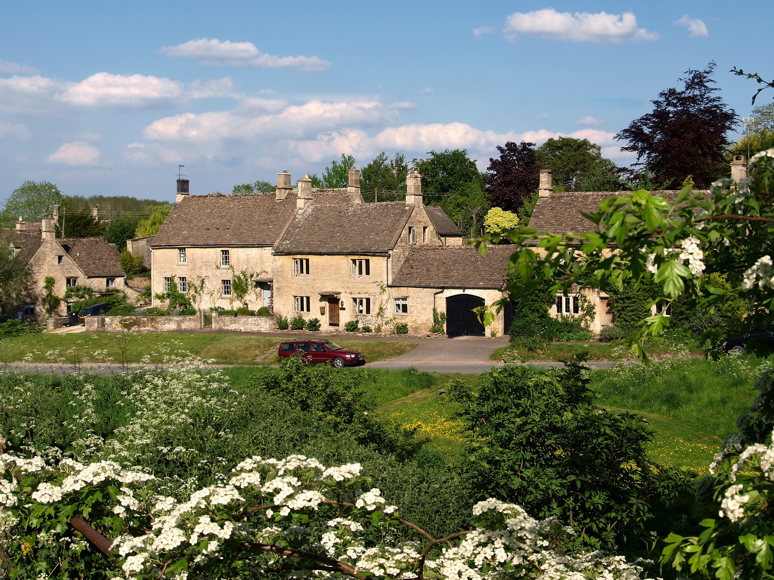 Cotswold village with stone houses and blooming trees HD Wallpaper