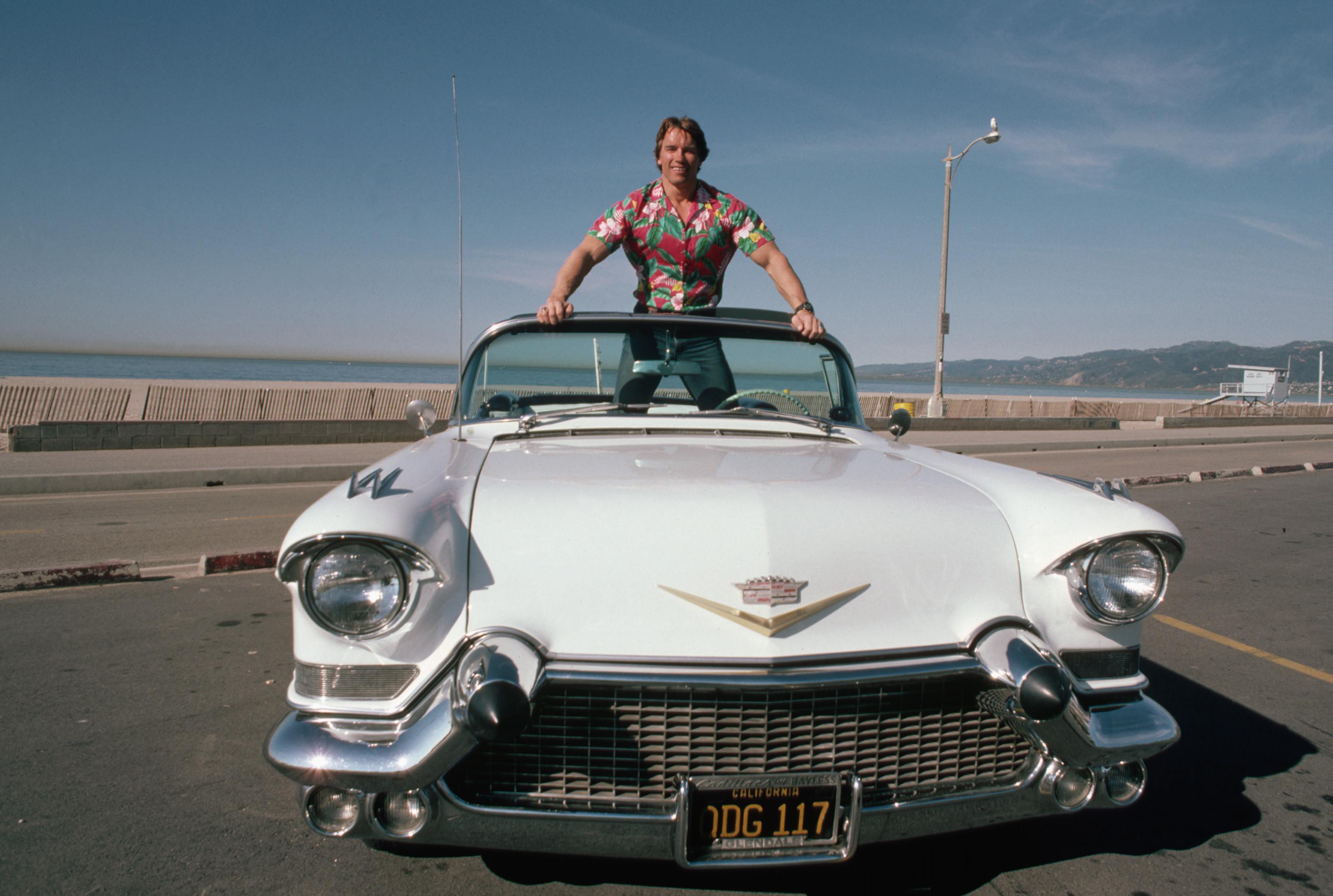 Arnold Schwarzenegger in a convertible Cadillac HD Wallpaper