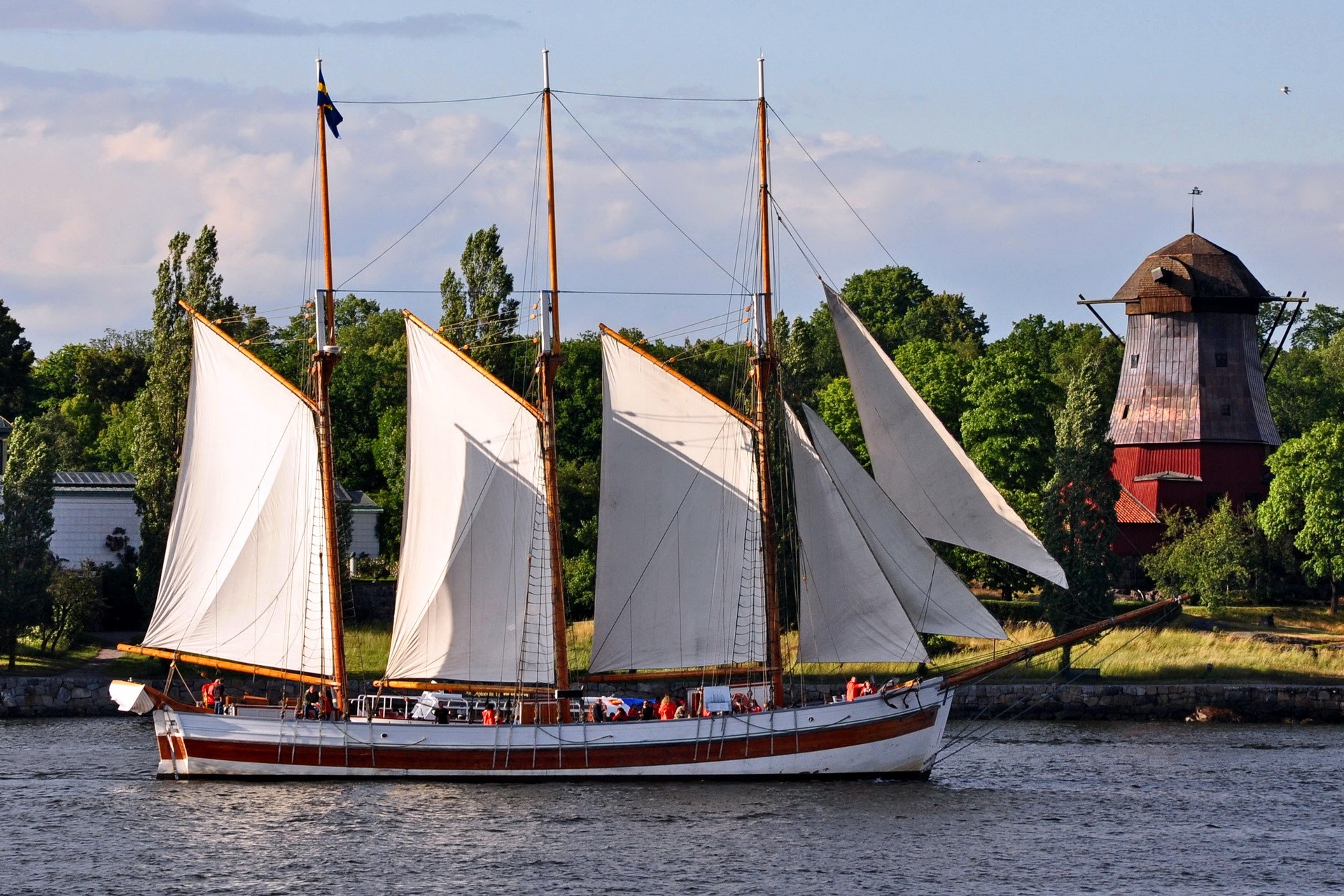 Sailboat with white sails near a red windmill HD Wallpaper