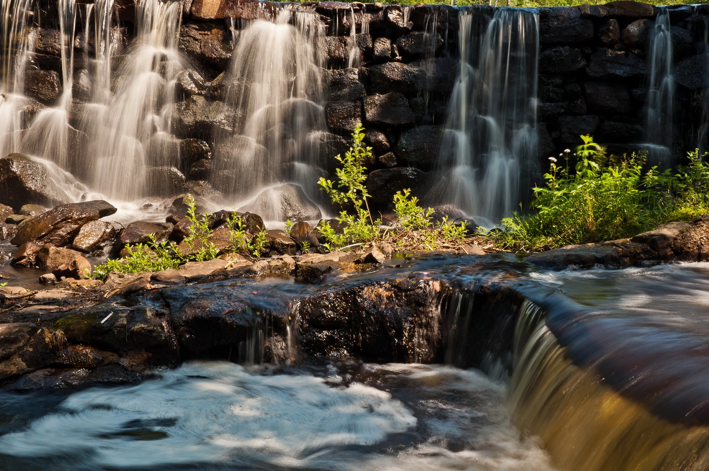Waterfalls cascading over rocks with greenery HD Wallpaper