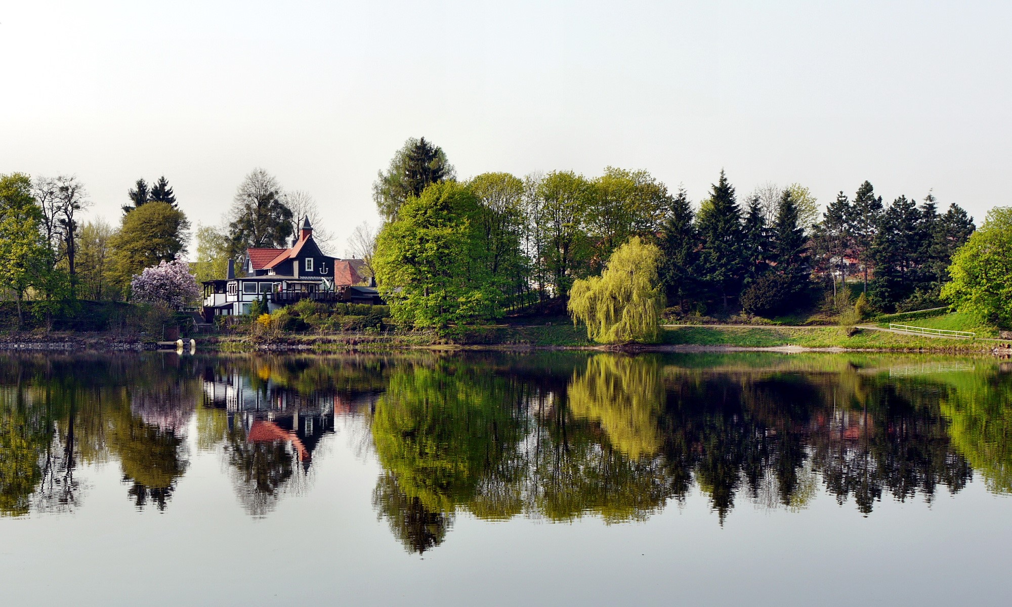 House and trees reflected in a lake in Germany HD Wallpaper