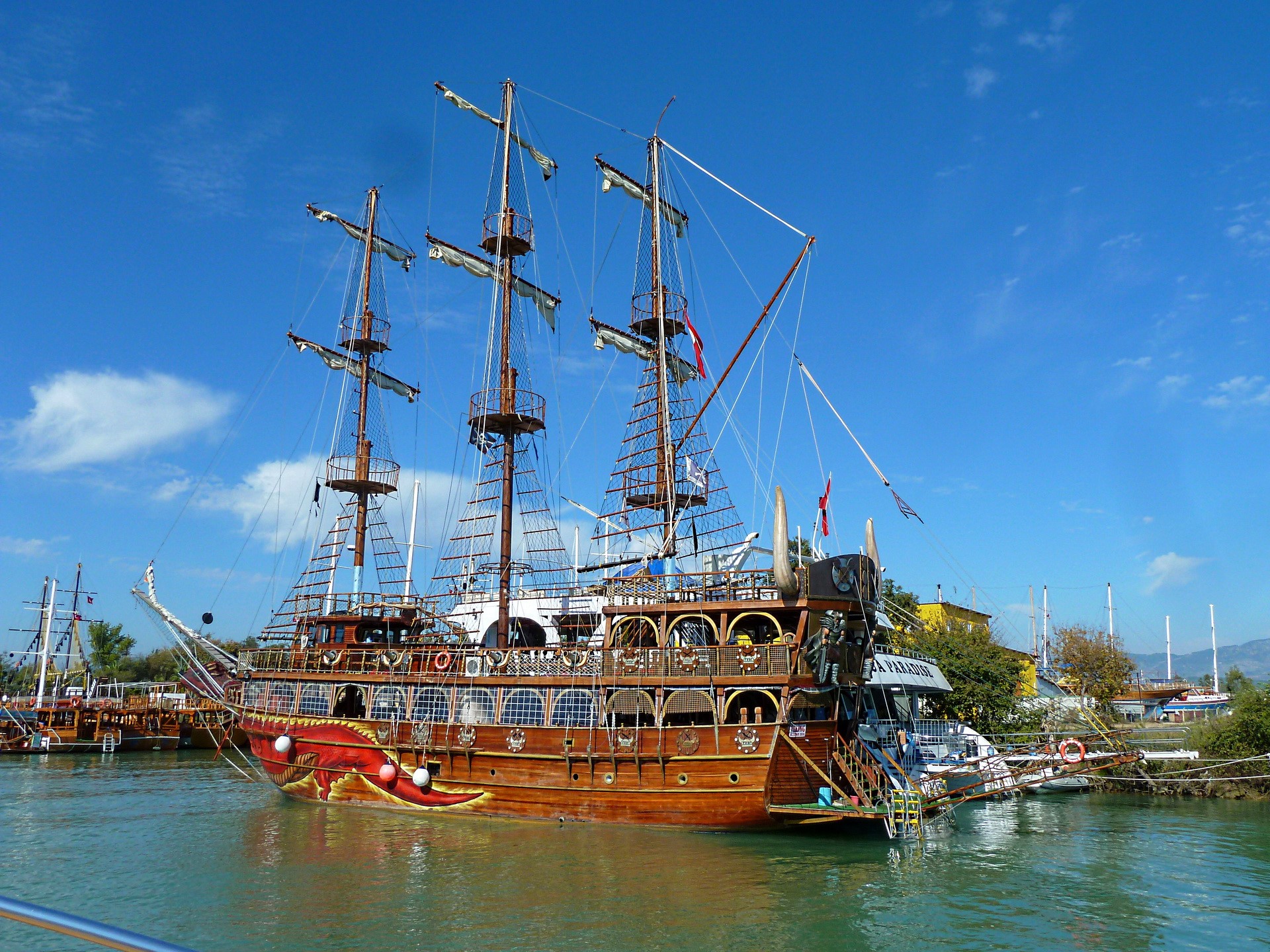 Wooden pirate ship sailing on turquoise water HD Wallpaper