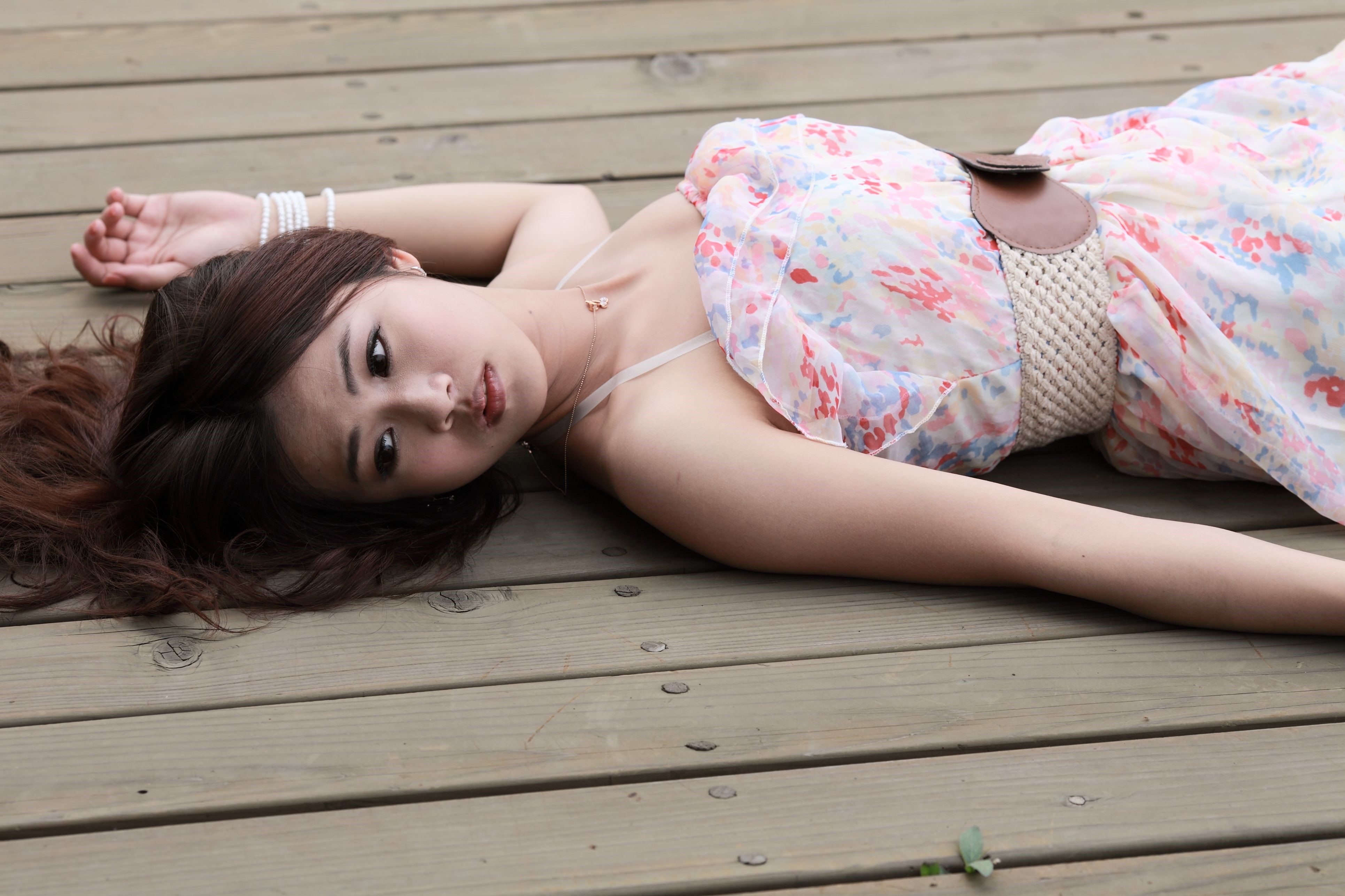 Asian woman in floral dress lying on wooden deck HD Wallpaper