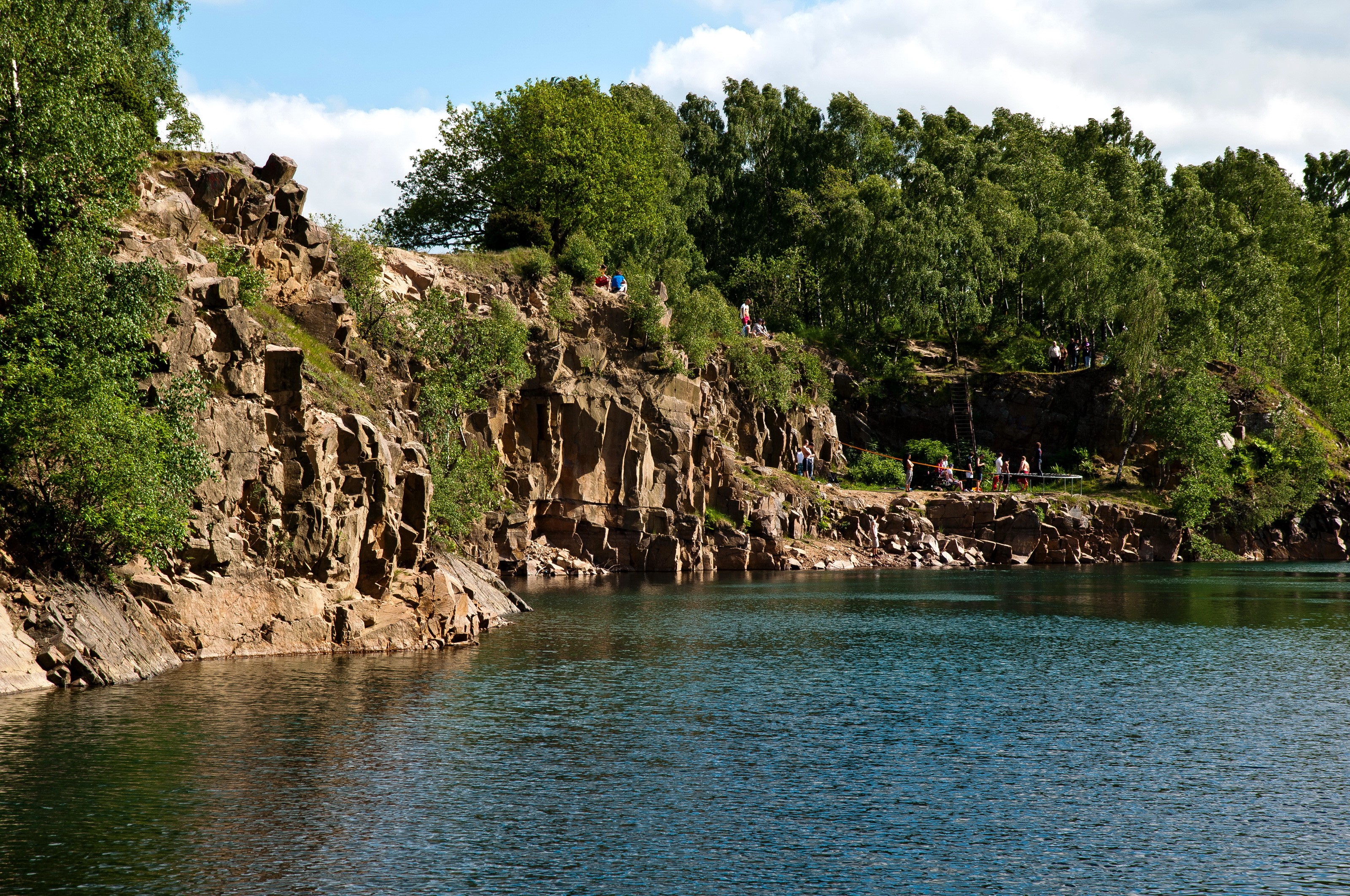 People jumping into a quarry lake HD Wallpaper