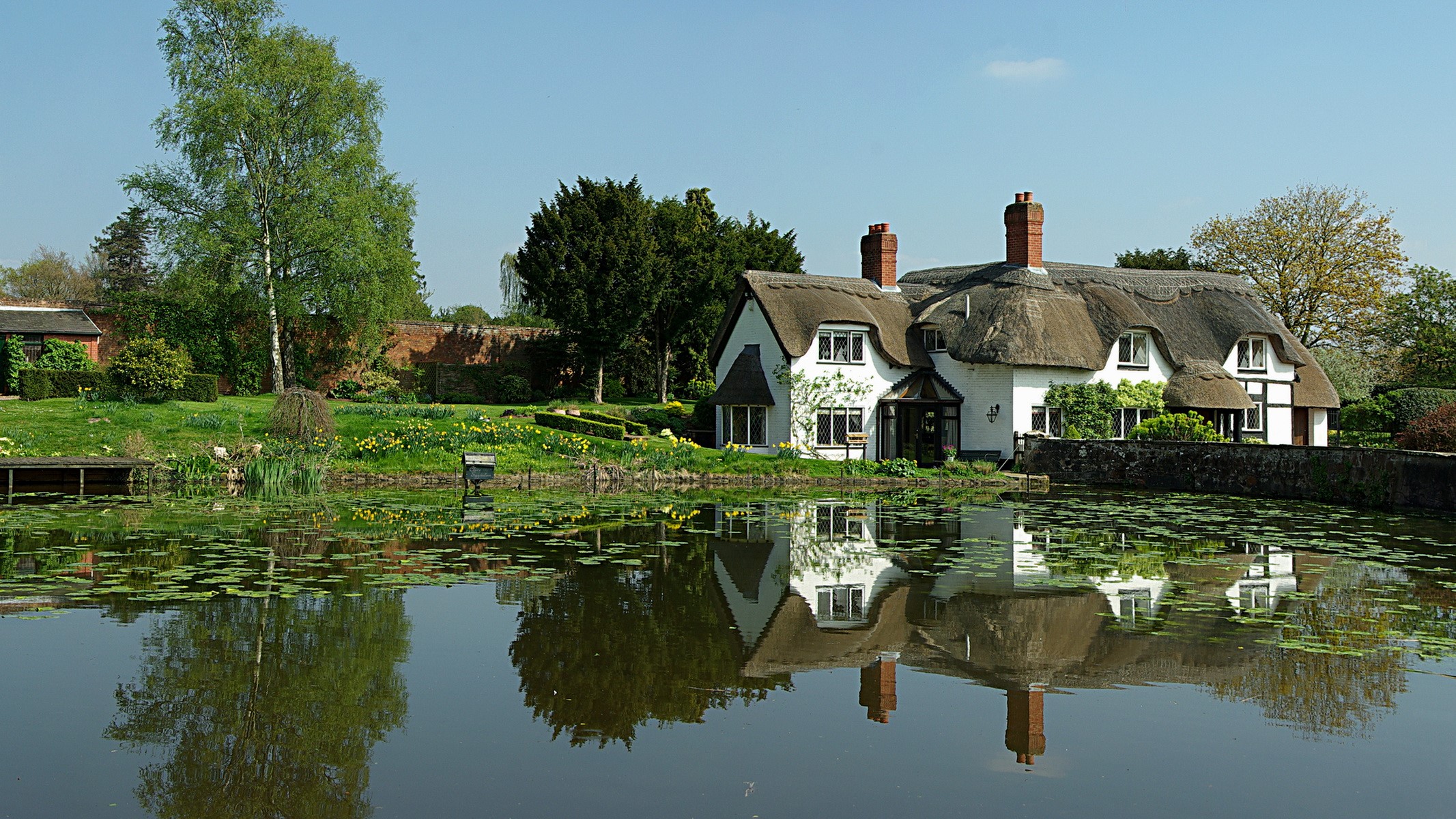 Thatched cottage by a pond in the United Kingdom HD Wallpaper