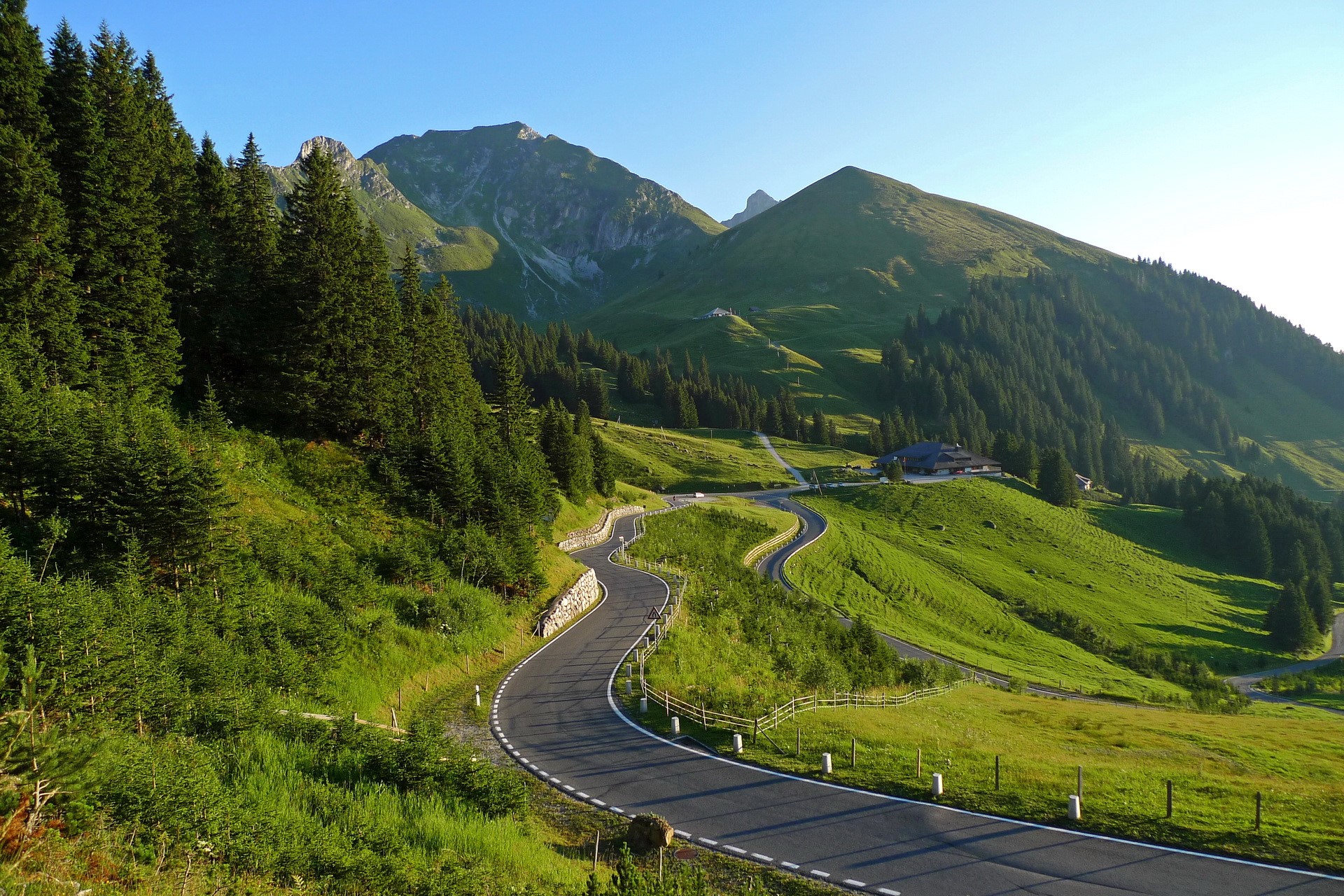 Winding mountain road through green hills in Switzerland HD Wallpaper