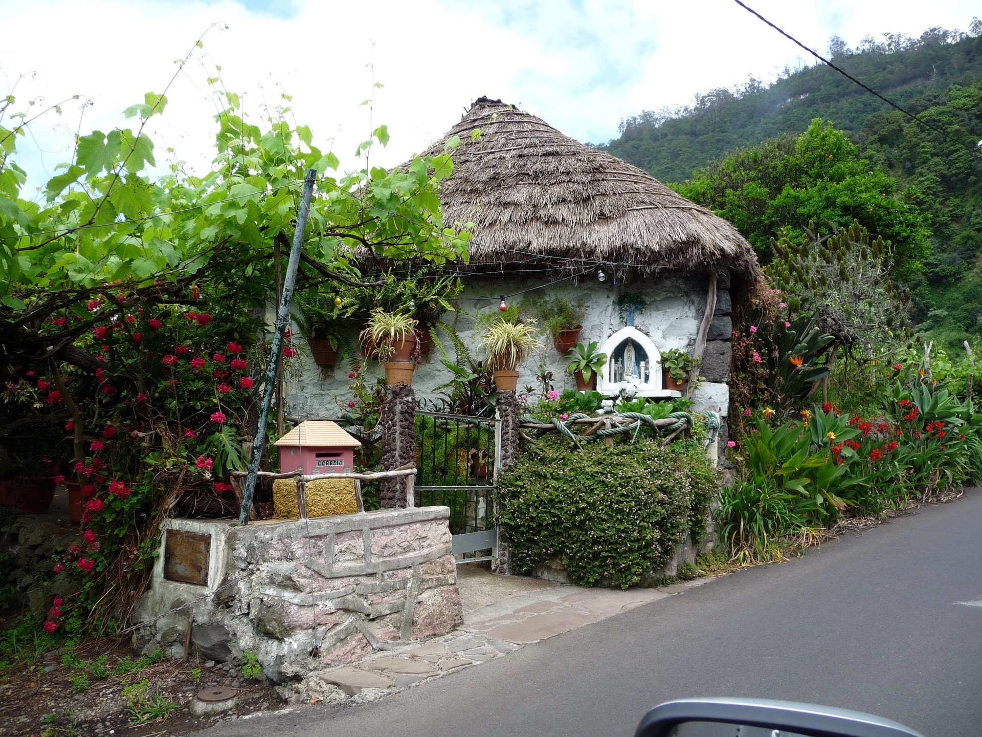Thatched roof house with garden and statue in Santana, Madeira HD Wallpaper