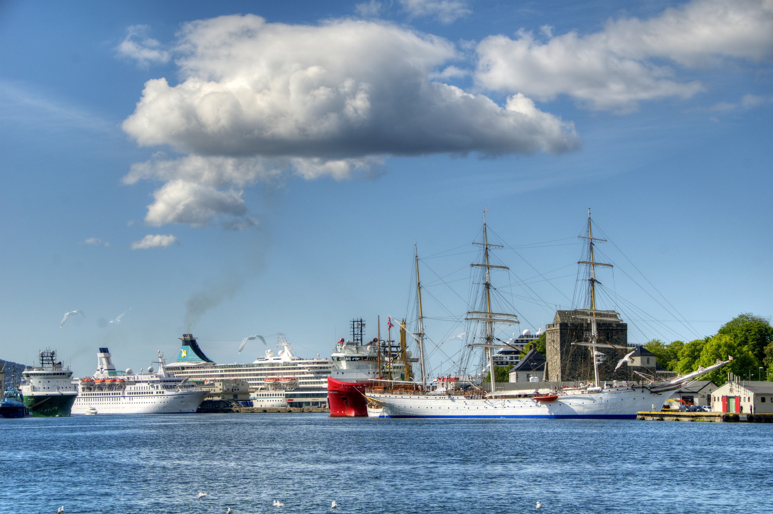 Ships docked in a harbor under a cloudy sky HD Wallpaper