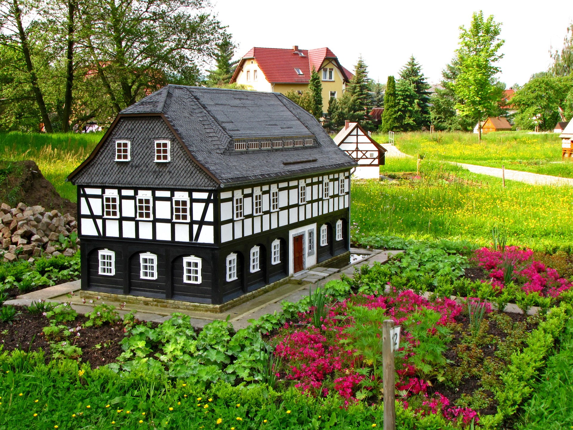 Miniature half-timbered house in a park with flowers HD Wallpaper