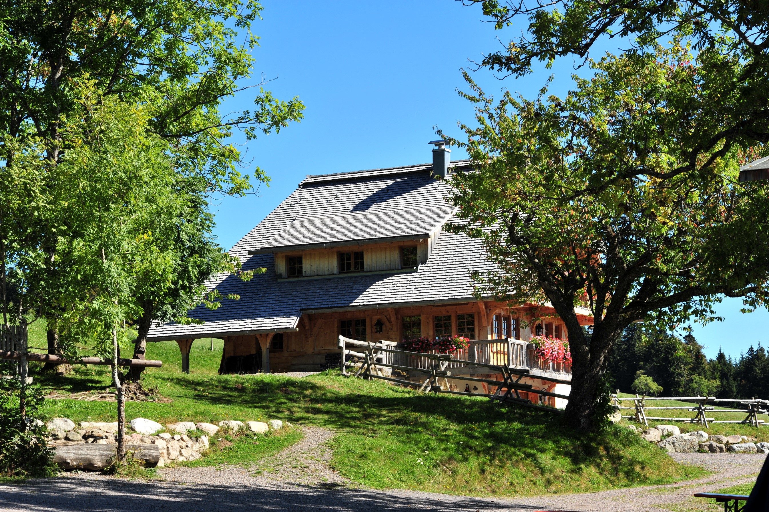 Wooden house with shingled roof in a green landscape HD Wallpaper