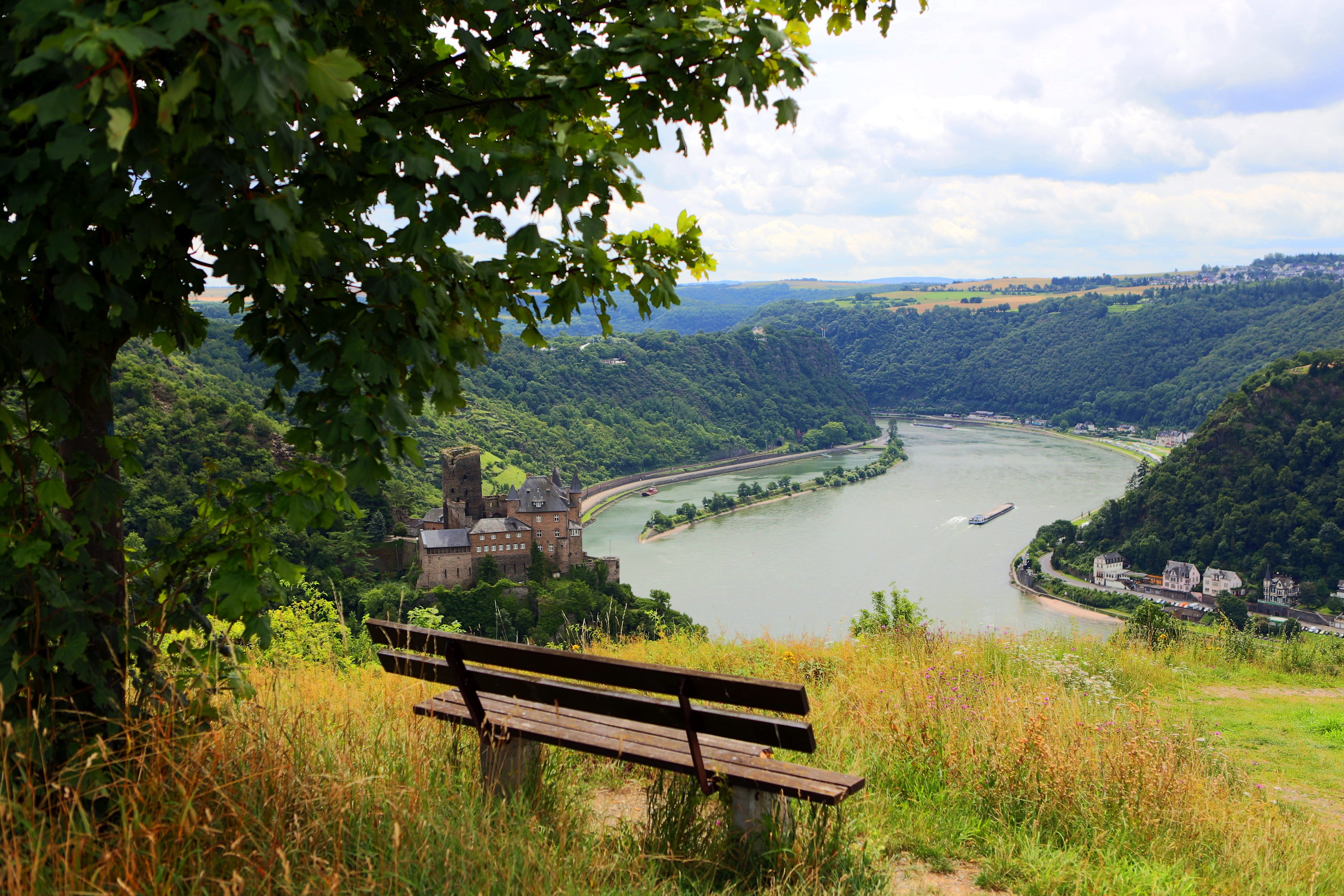 Castle overlooking a river valley with a bench in the foreground HD Wallpaper