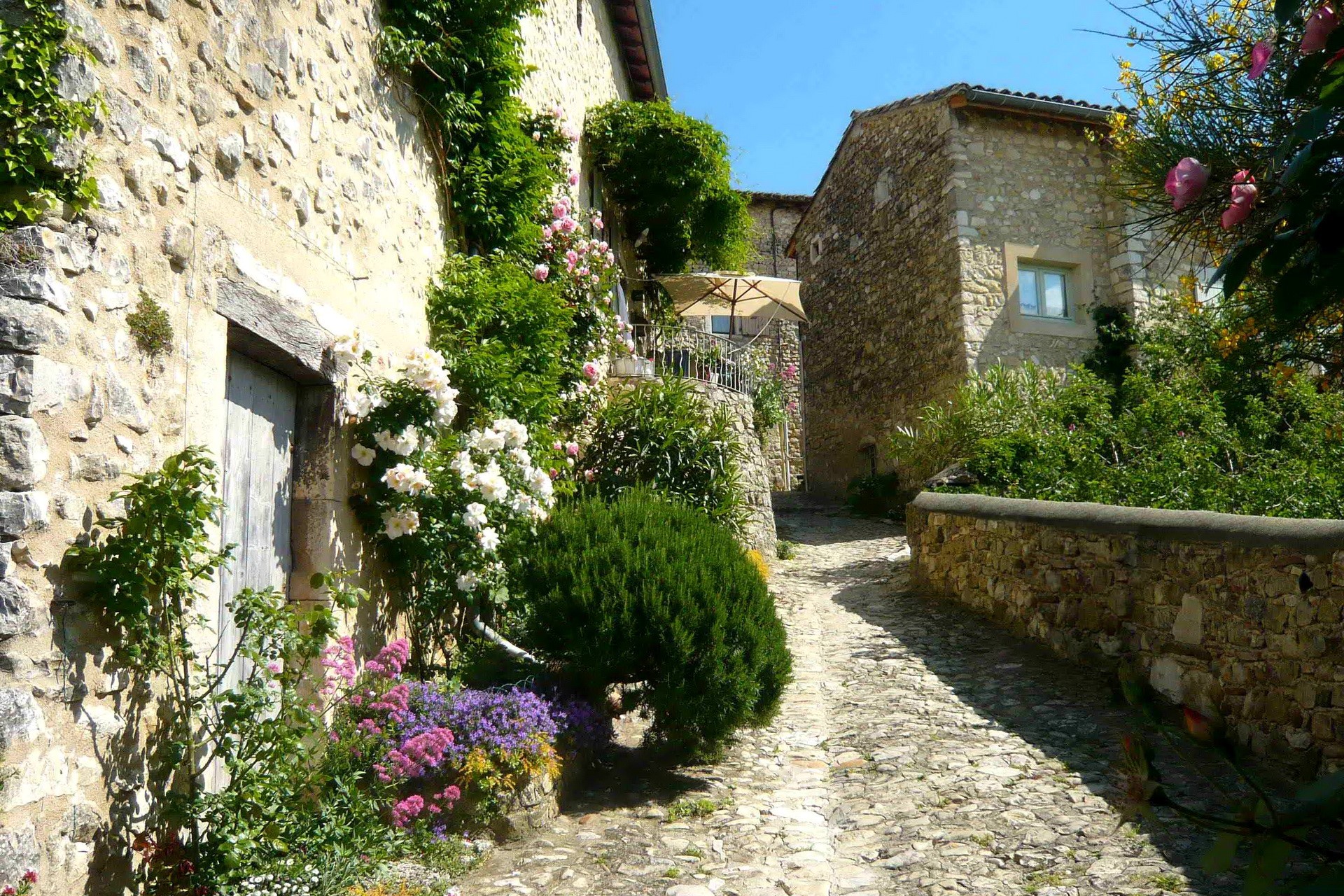 Stone village street with flowers and buildings in France HD Wallpaper