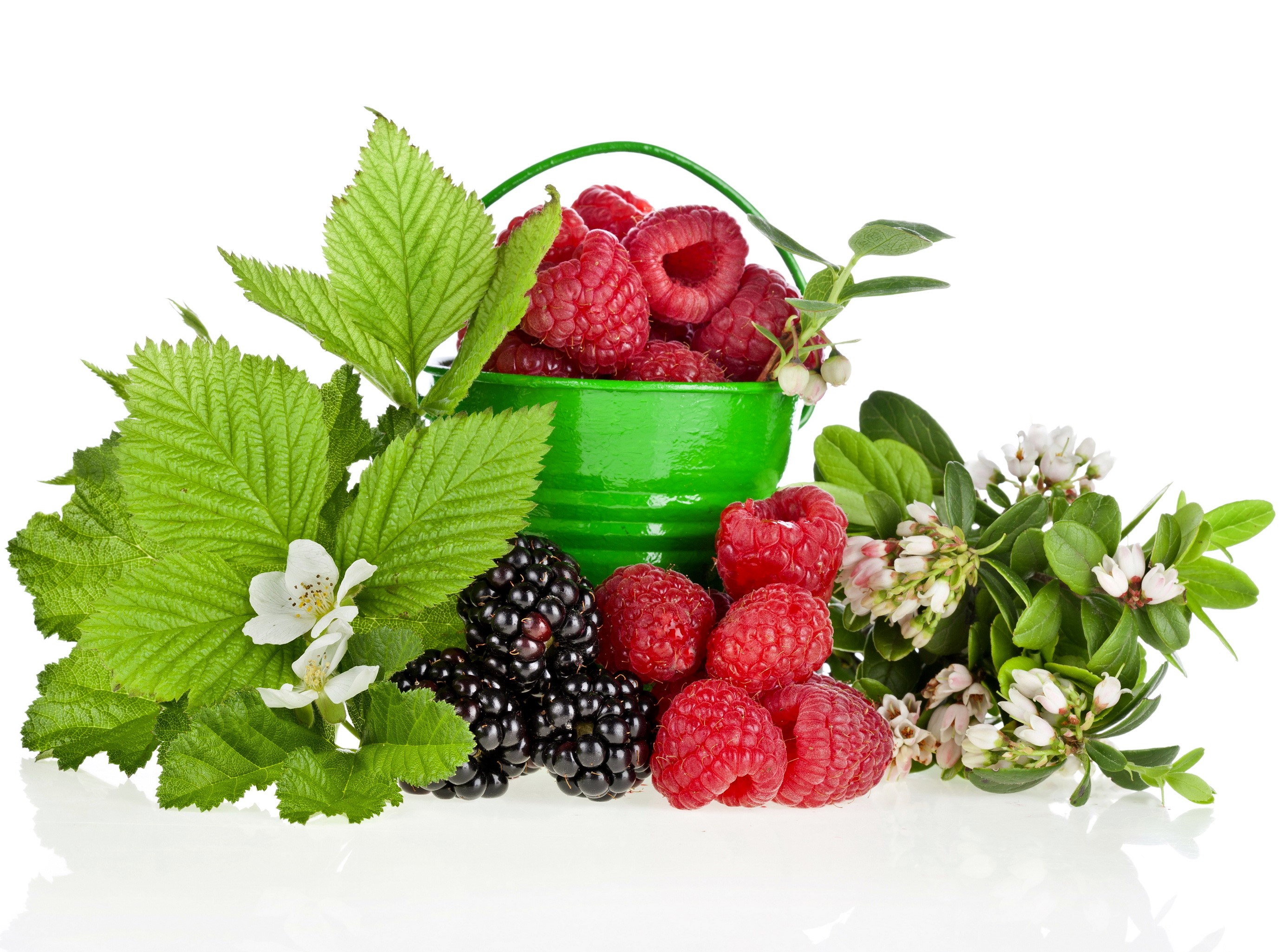 Raspberries and blackberries in a green bucket with leaves and flowers HD Wallpaper