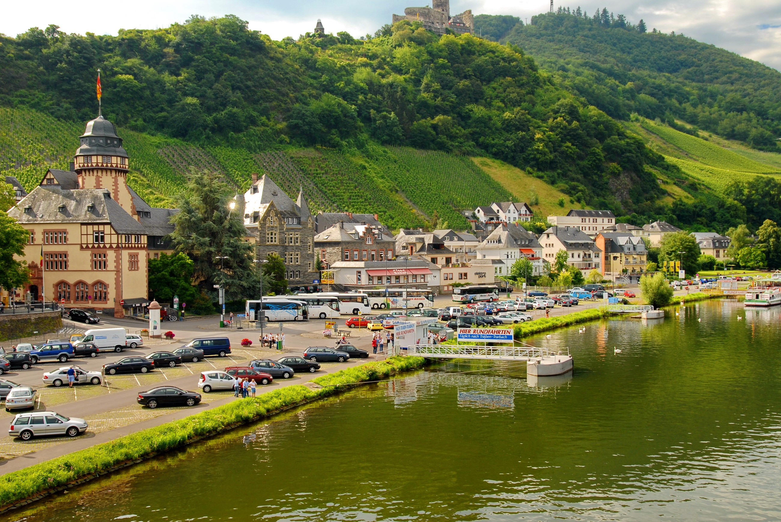 Town on a river with vineyards and castle ruins HD Wallpaper